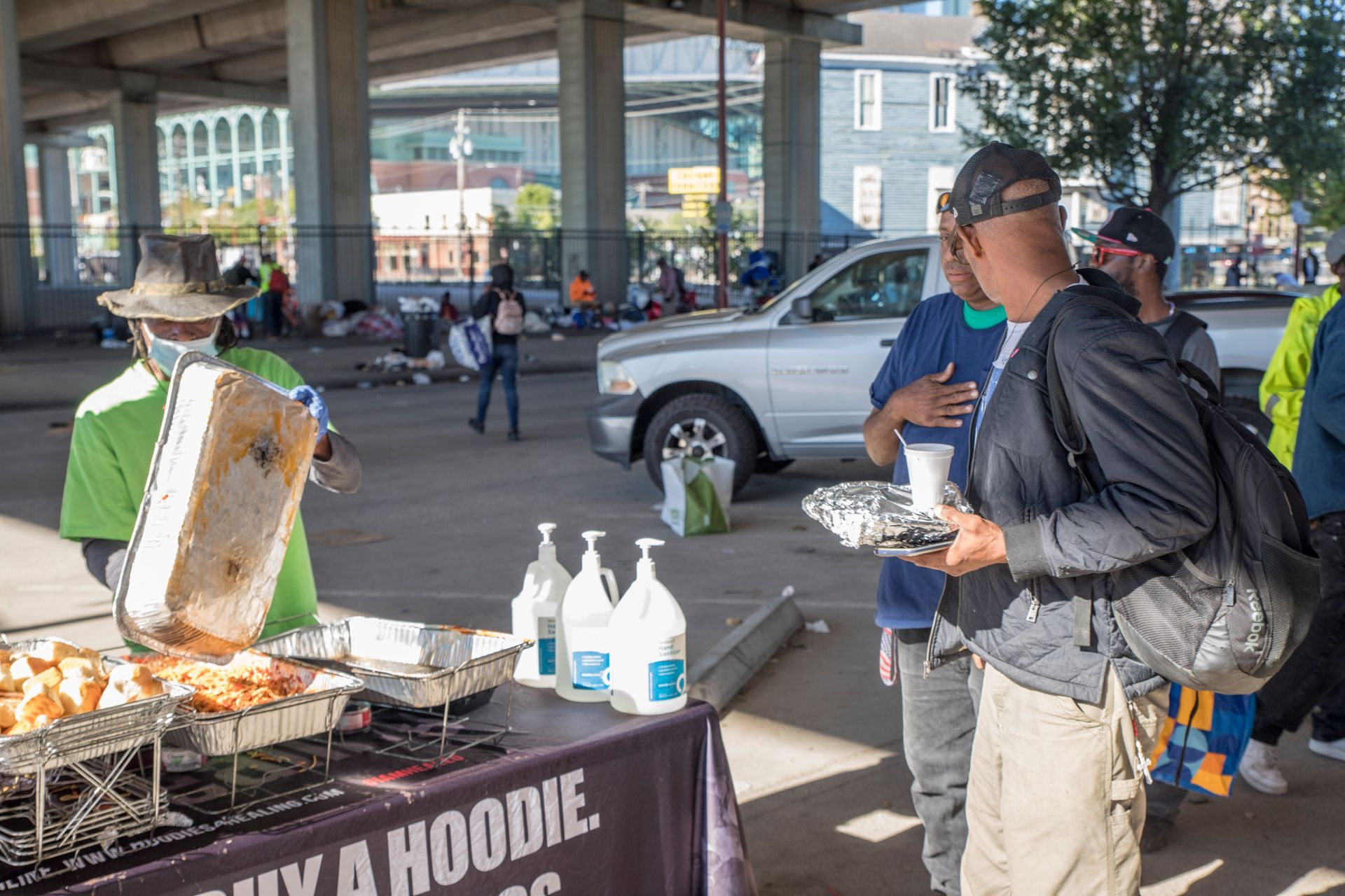 A group of people are standing around a table holding plates of food.