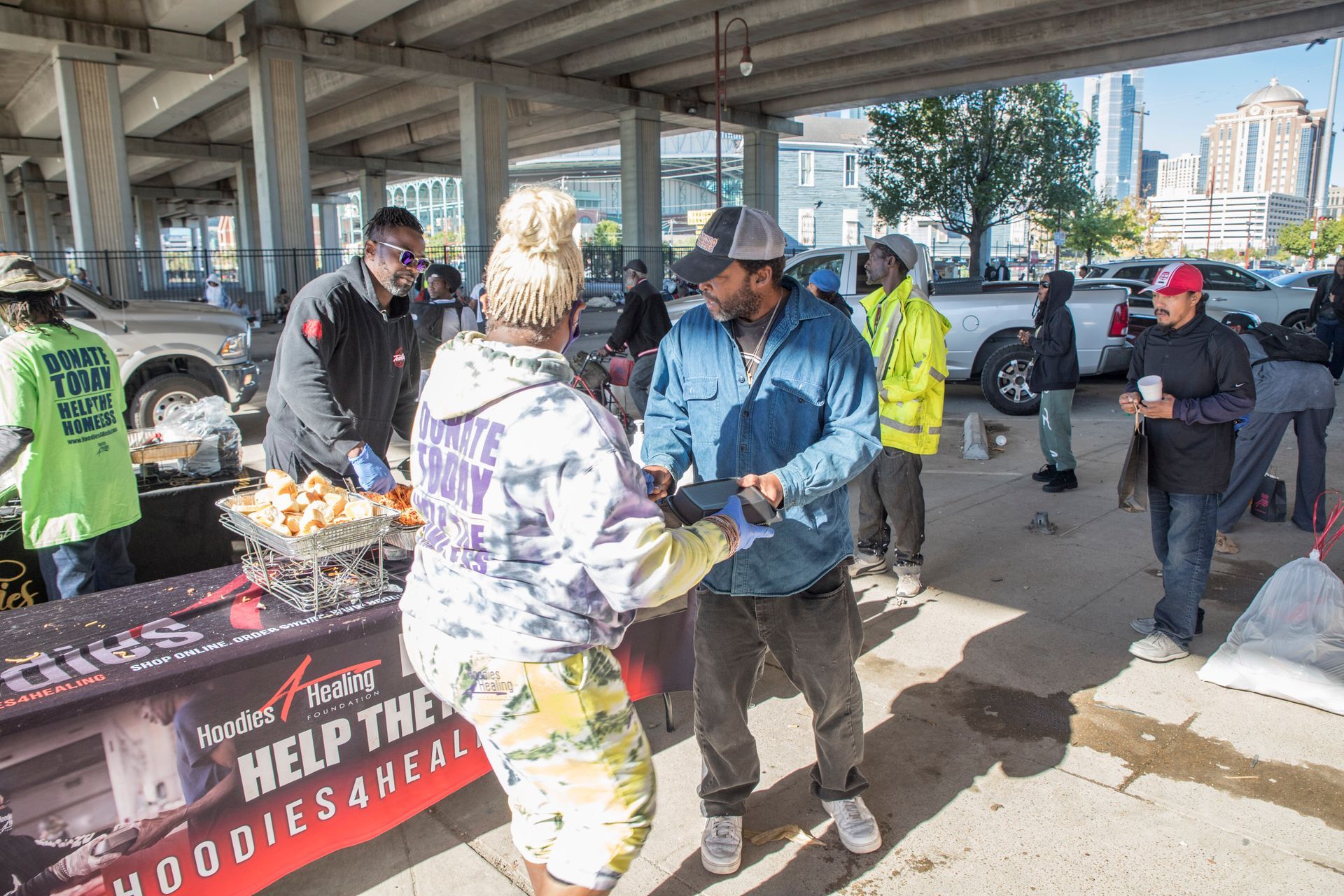 A group of people are standing around a table in a parking lot.