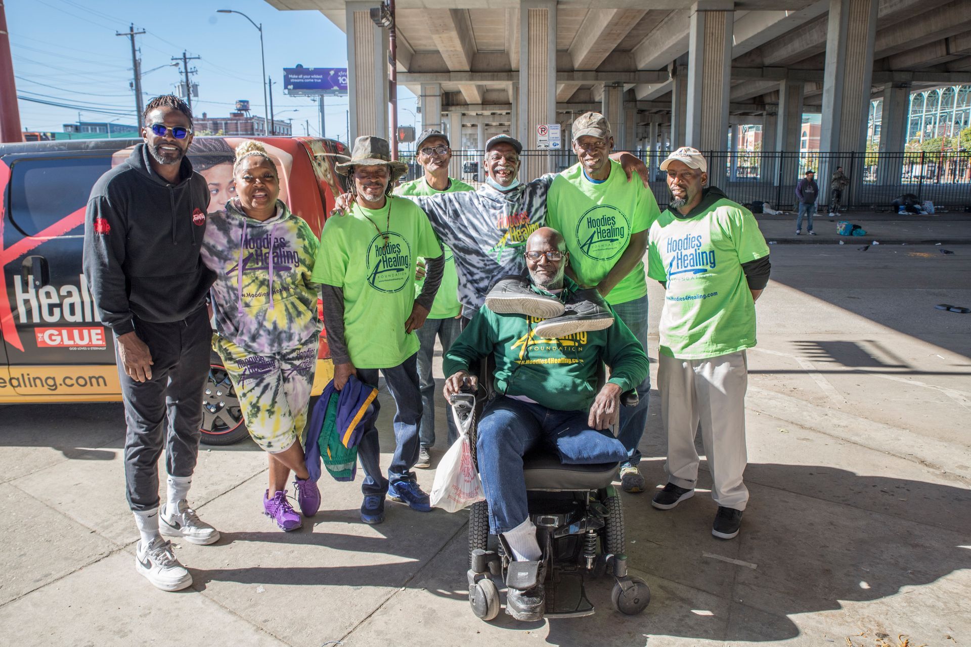 A group of people are posing for a picture with a man in a wheelchair.
