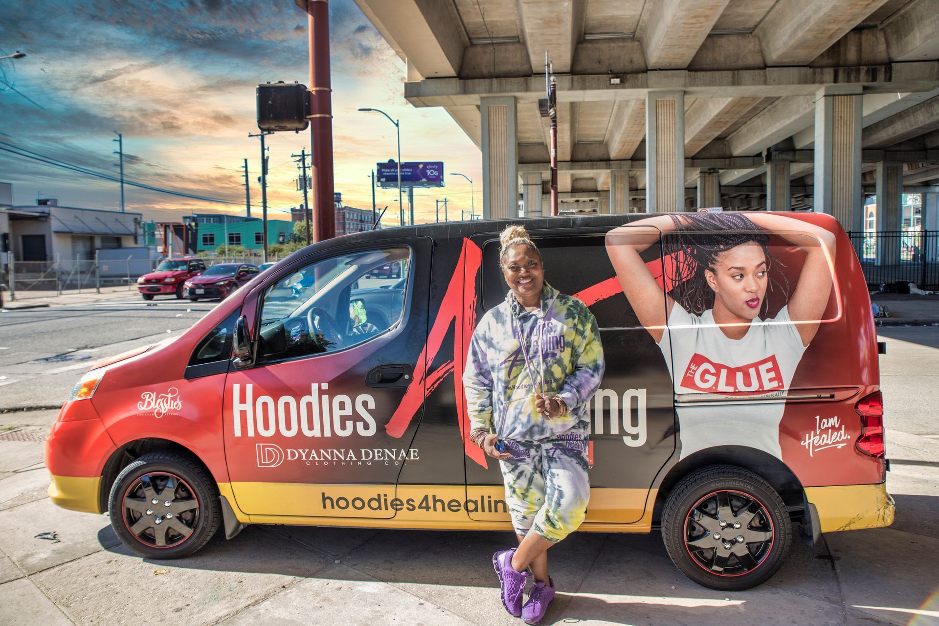 A woman is sitting on the back of a hoodies van.