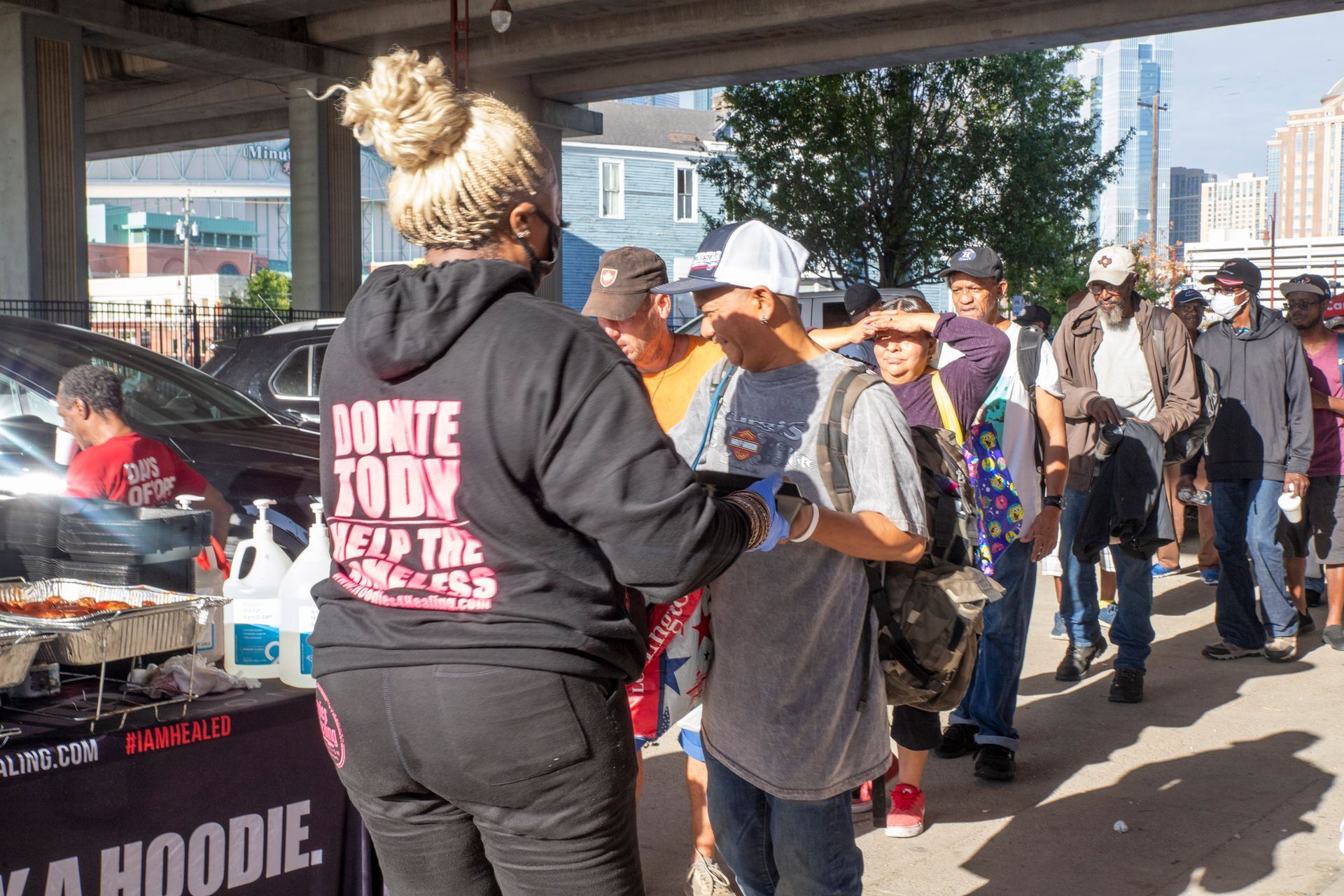A woman in a hoodie is standing in front of a crowd of people.