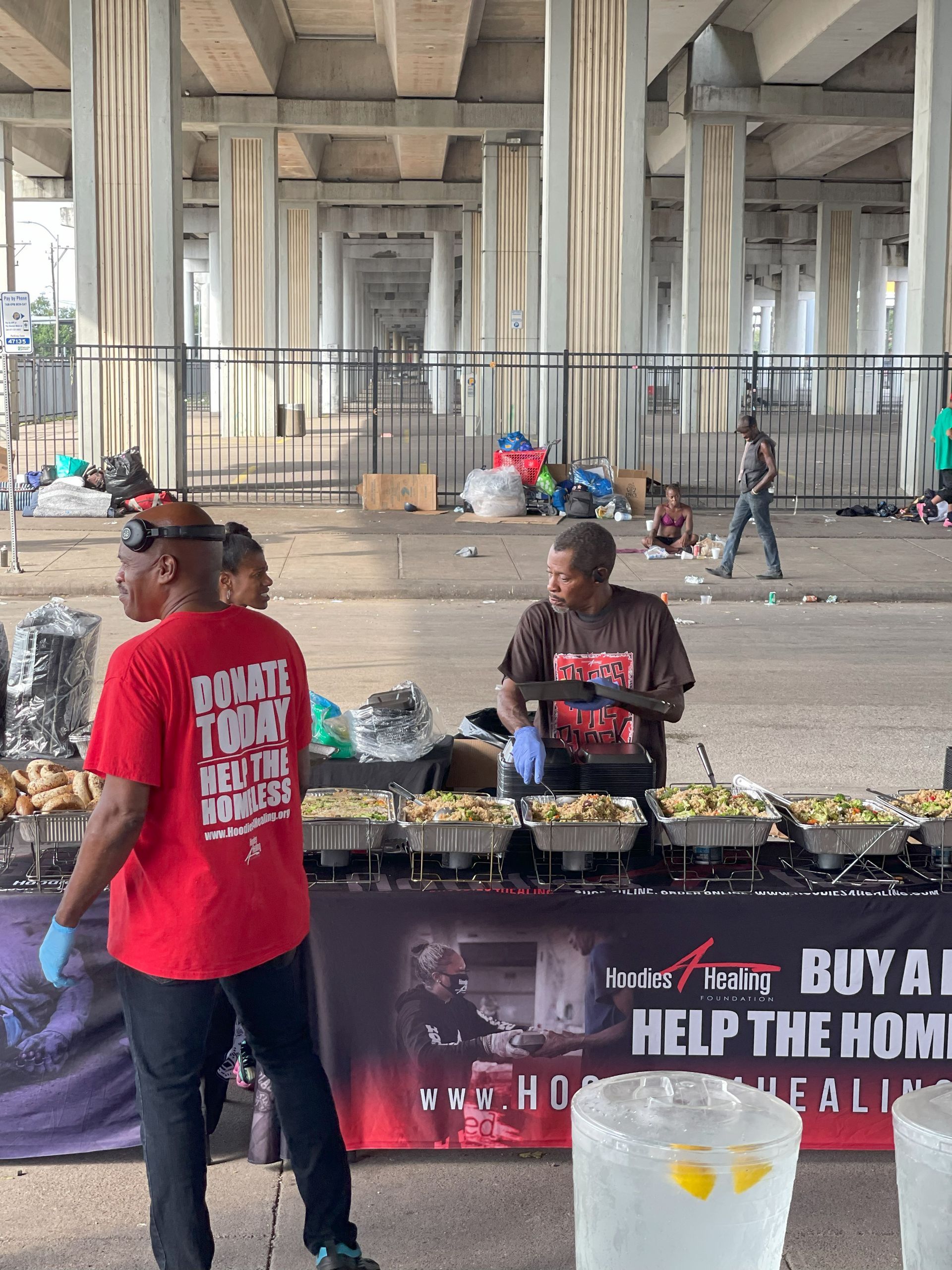 A man in a red shirt is standing in front of a table with food on it.