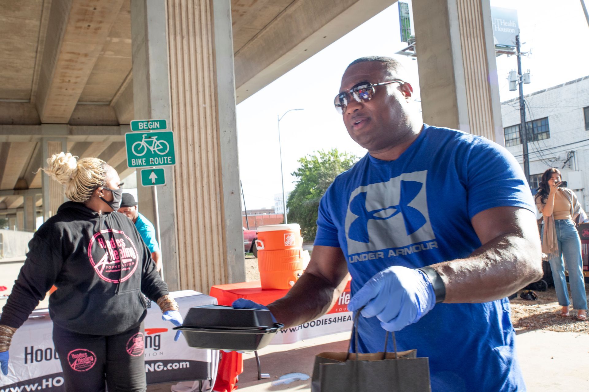 A man wearing a blue under armour shirt is standing next to a woman.