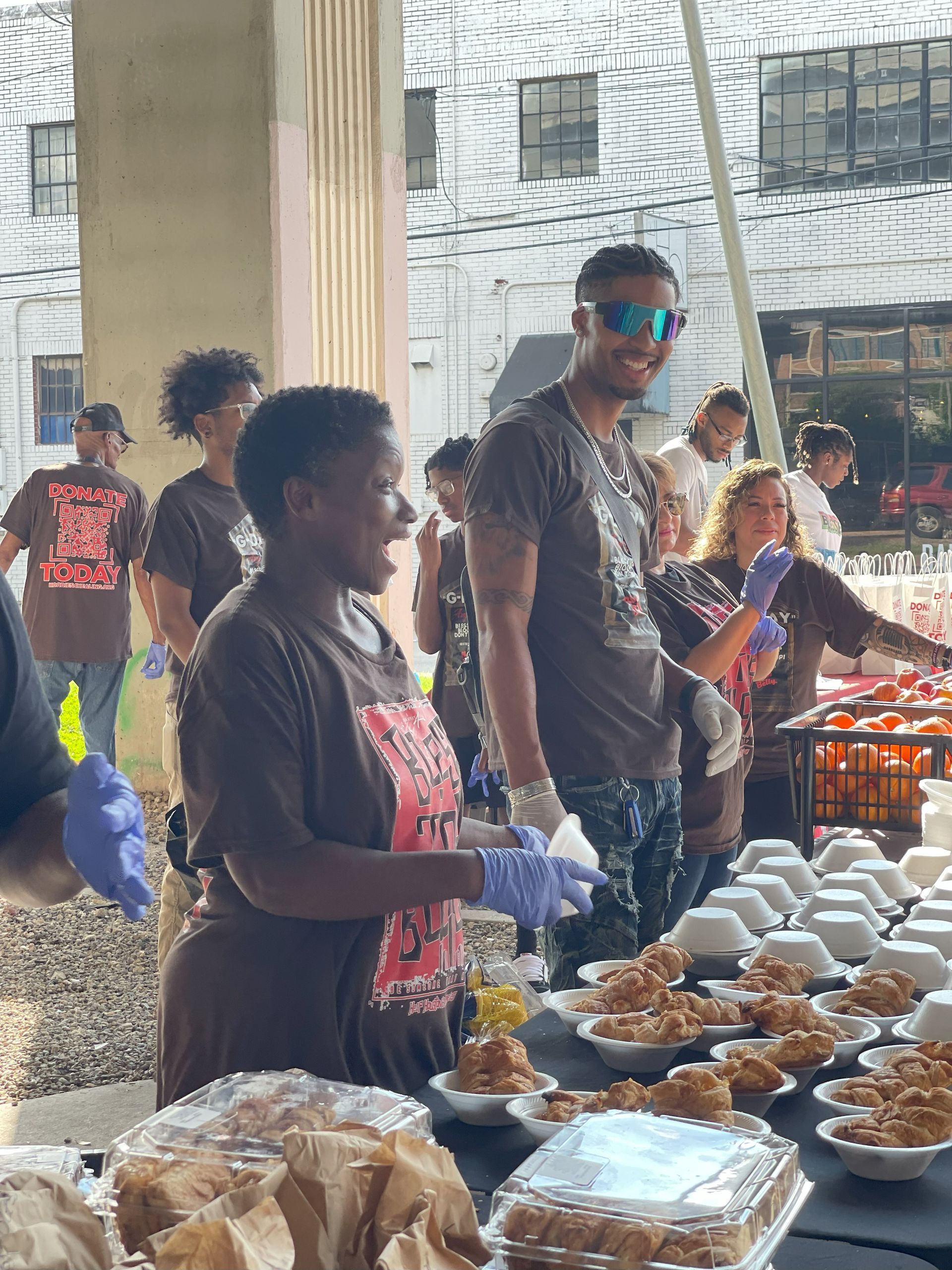 A group of people are standing around a table with plates of food.