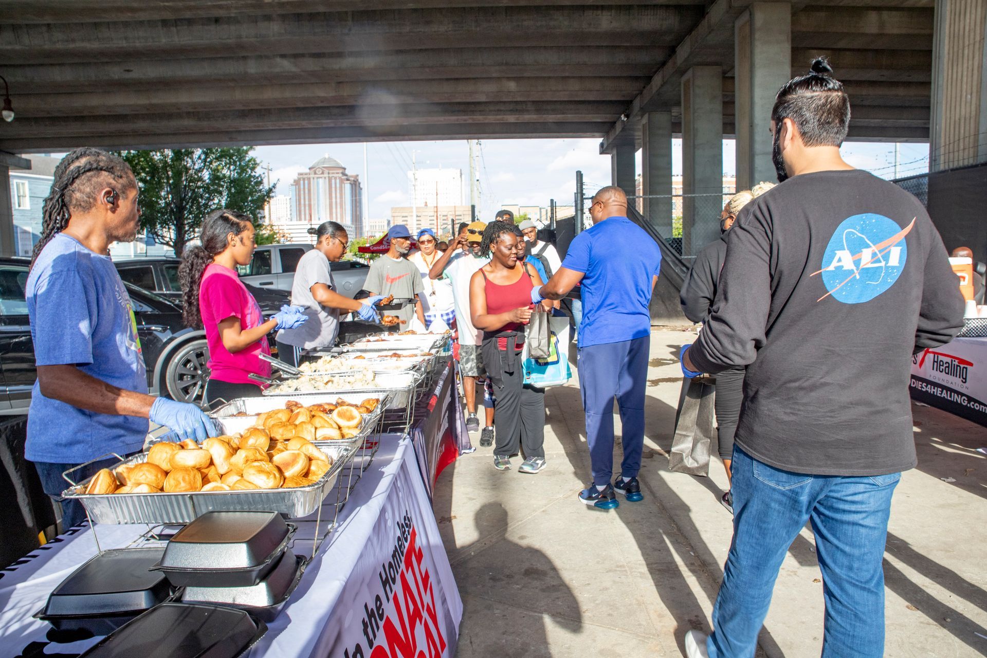 A man in a nasa shirt is standing in front of a table filled with food.
