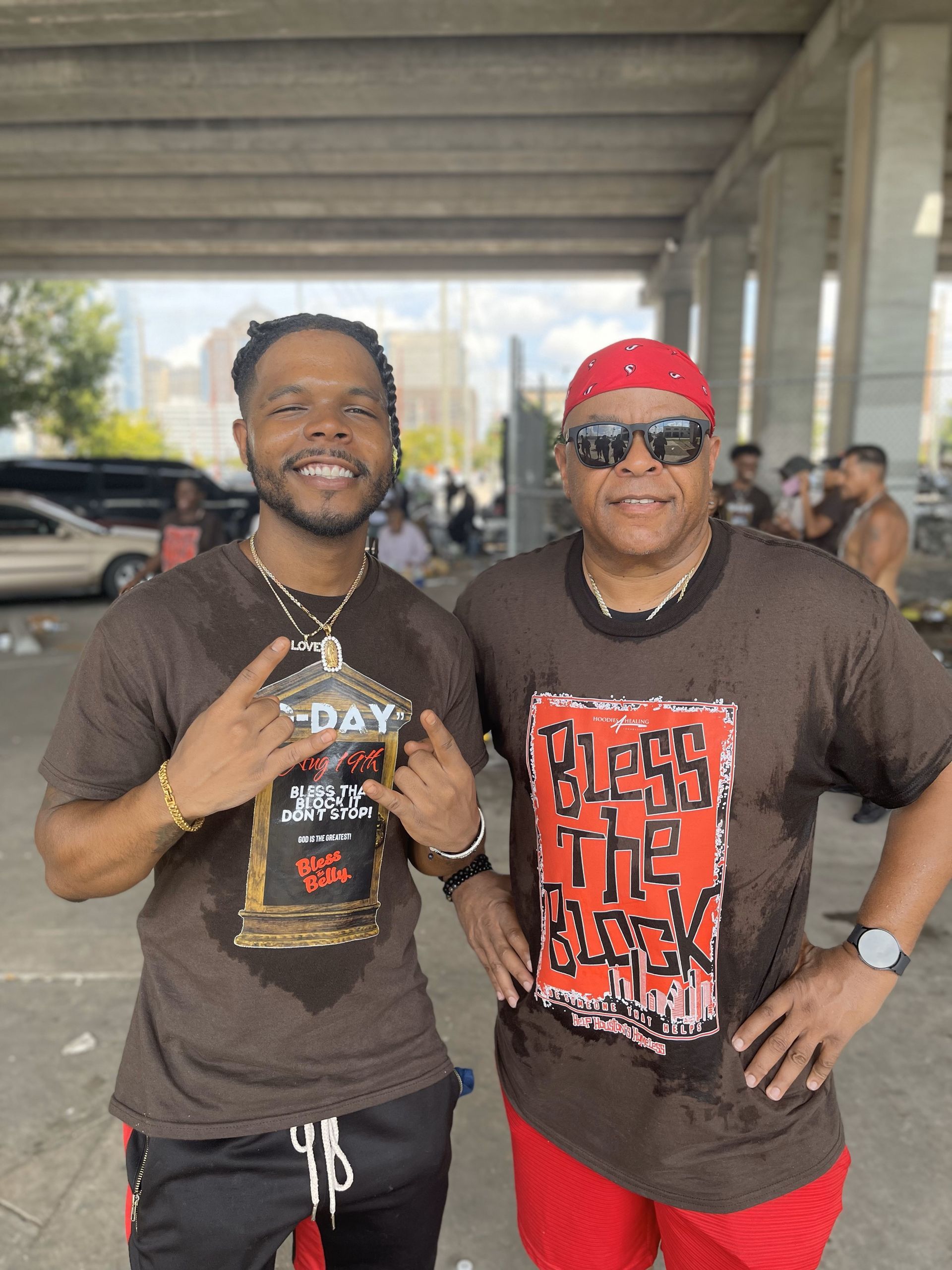 Two men are standing next to each other in a parking lot.