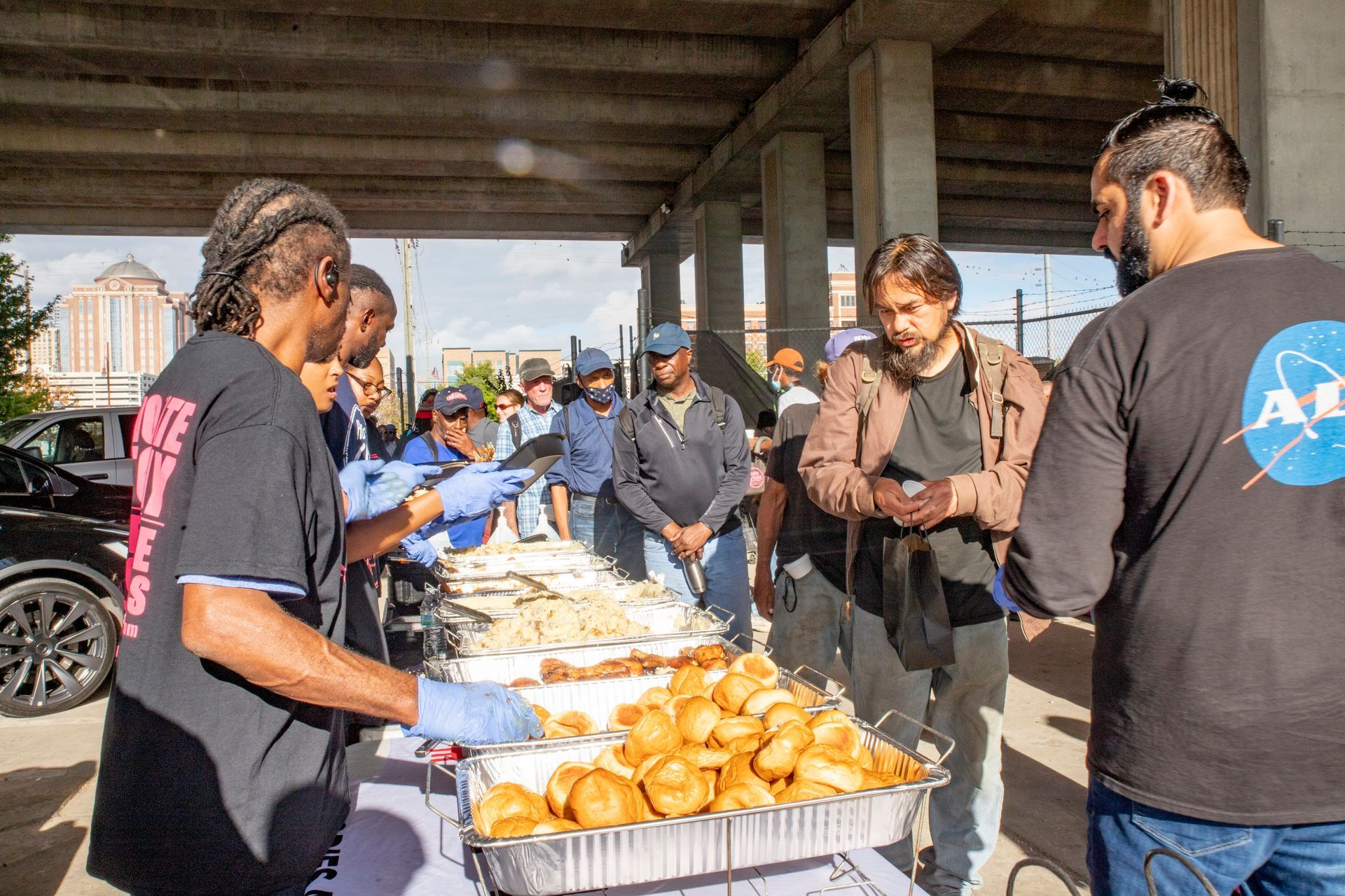 A group of people are standing around a table serving food.