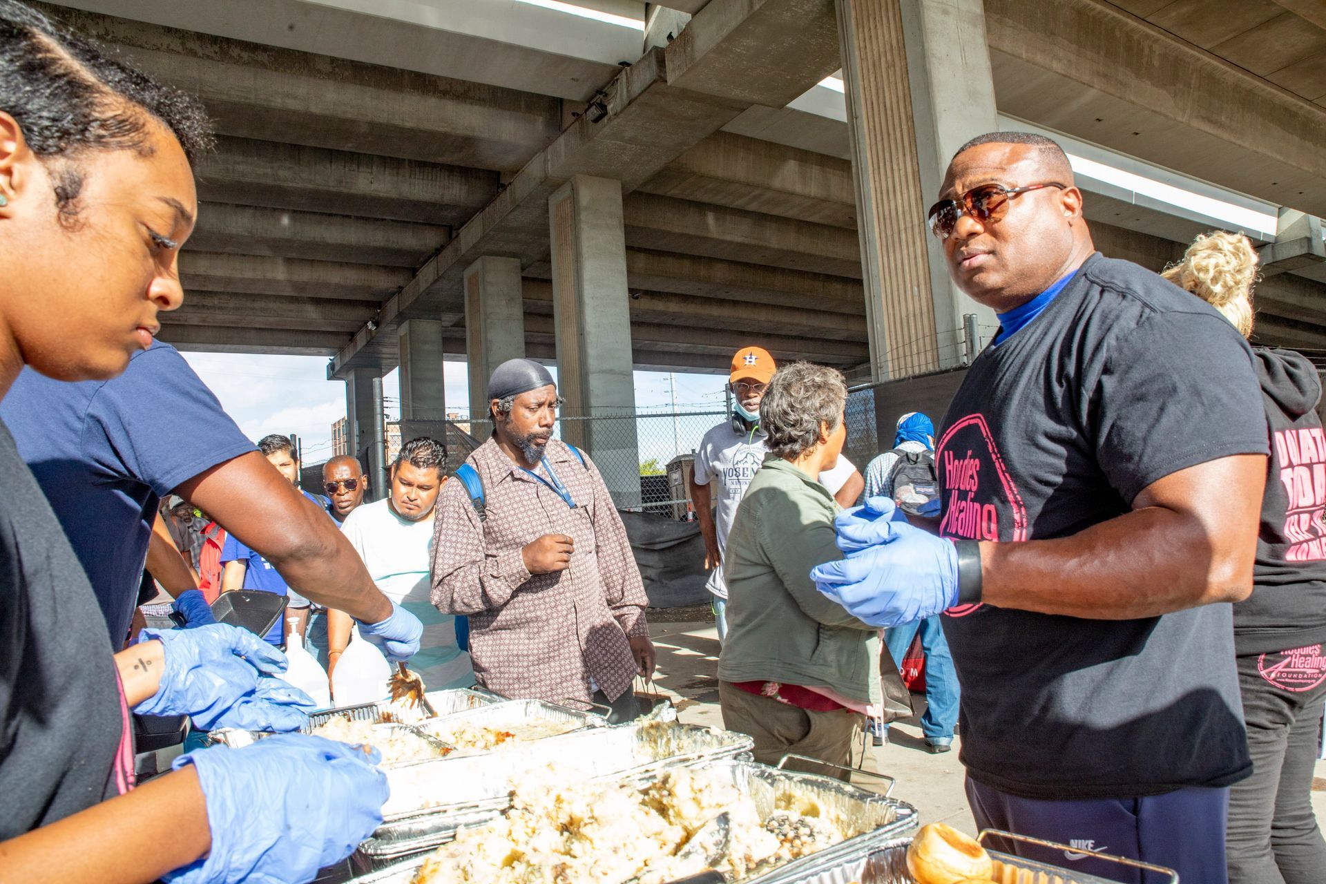 A group of people are standing around a table with food.
