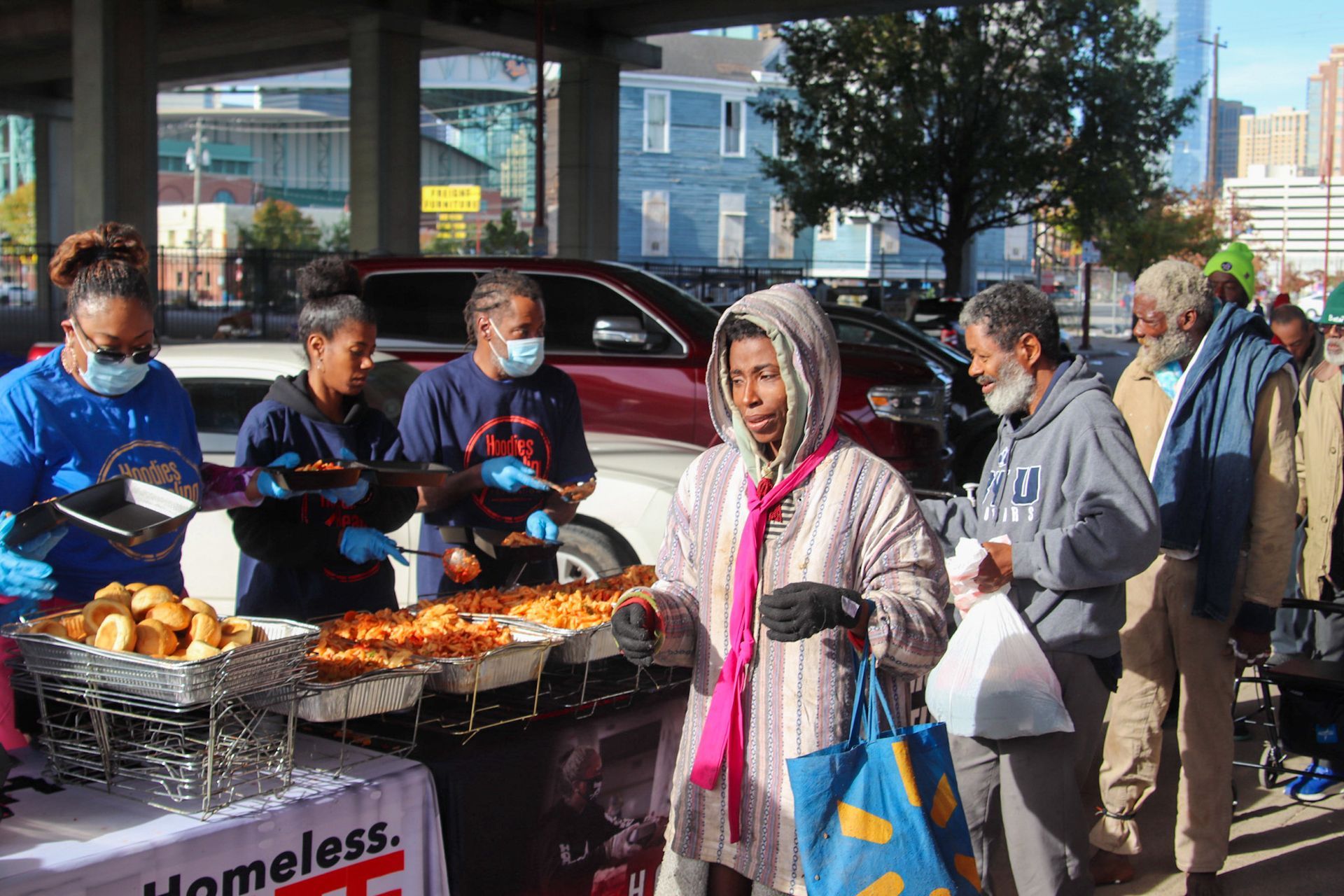A group of people are standing around a table with food.