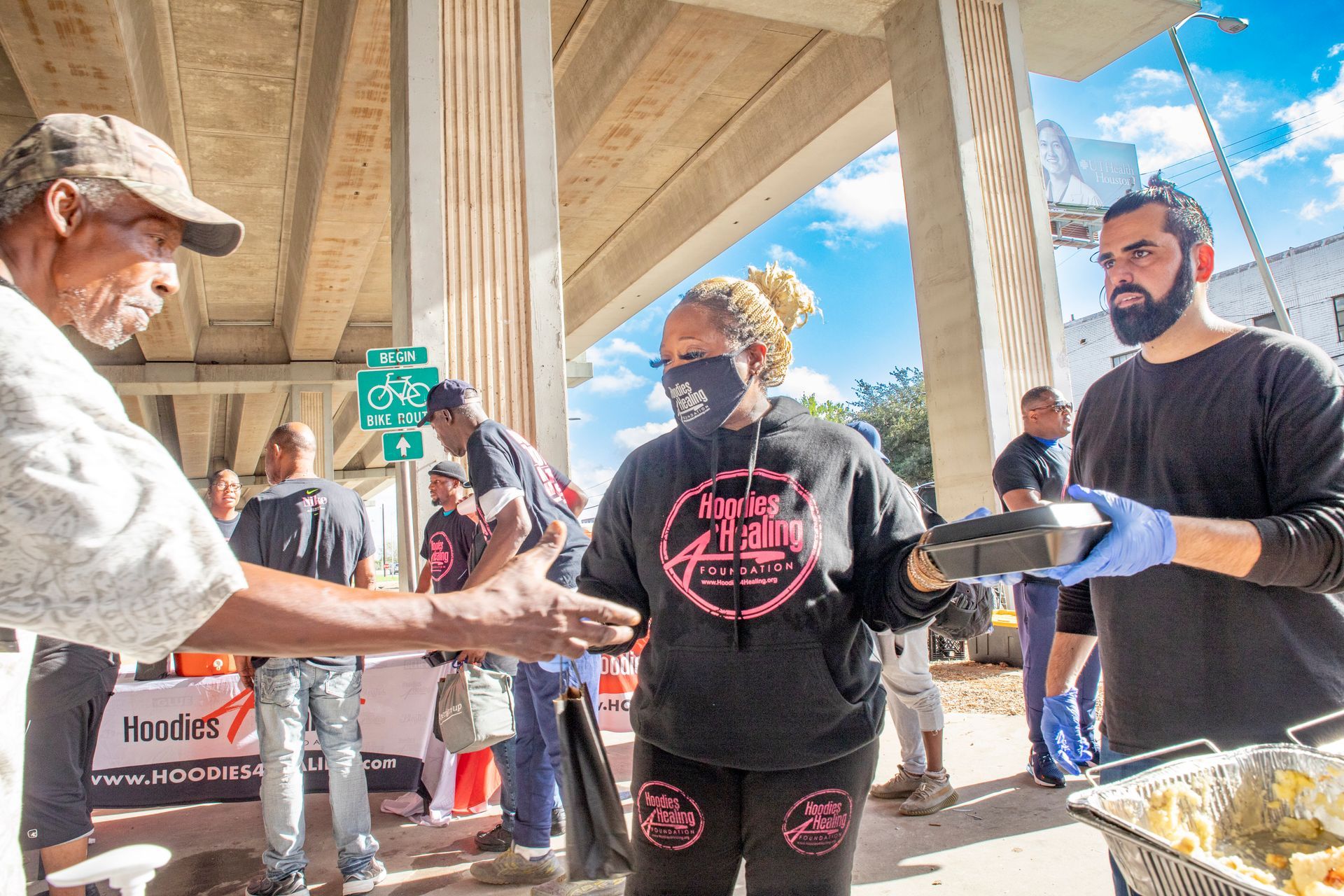 A man is giving a woman a plate of food while wearing a mask.