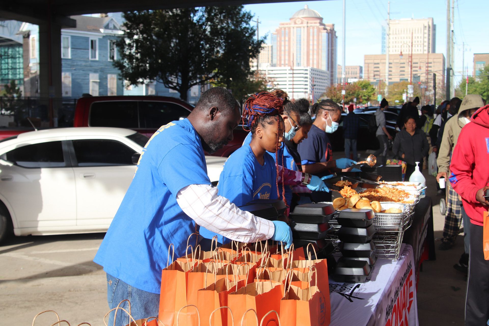 A group of people are standing around a table filled with bags of food.