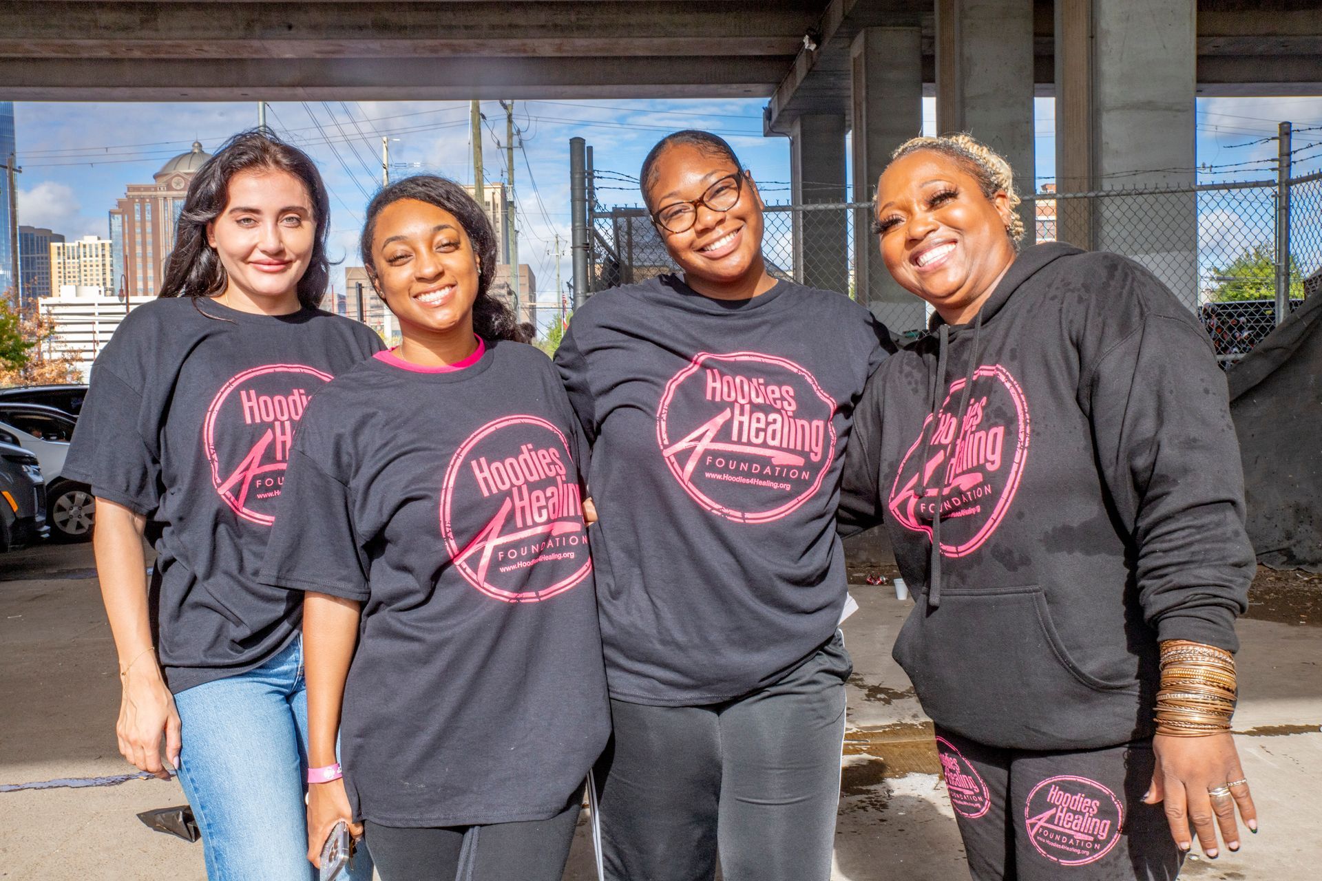 A group of women wearing black shirts and hoodies are posing for a picture.