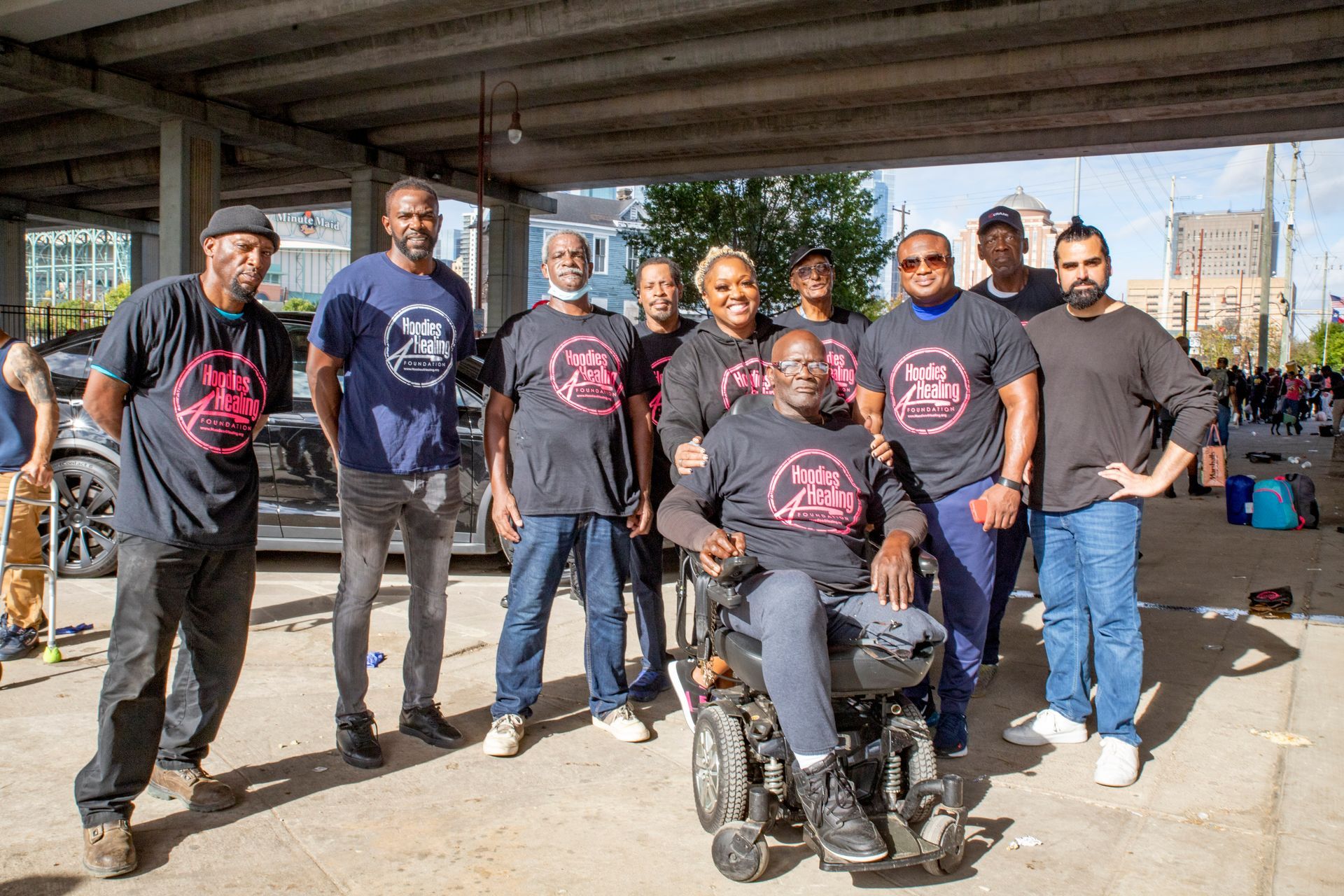 A group of people are posing for a picture in a parking garage . one of the people is in a wheelchair.