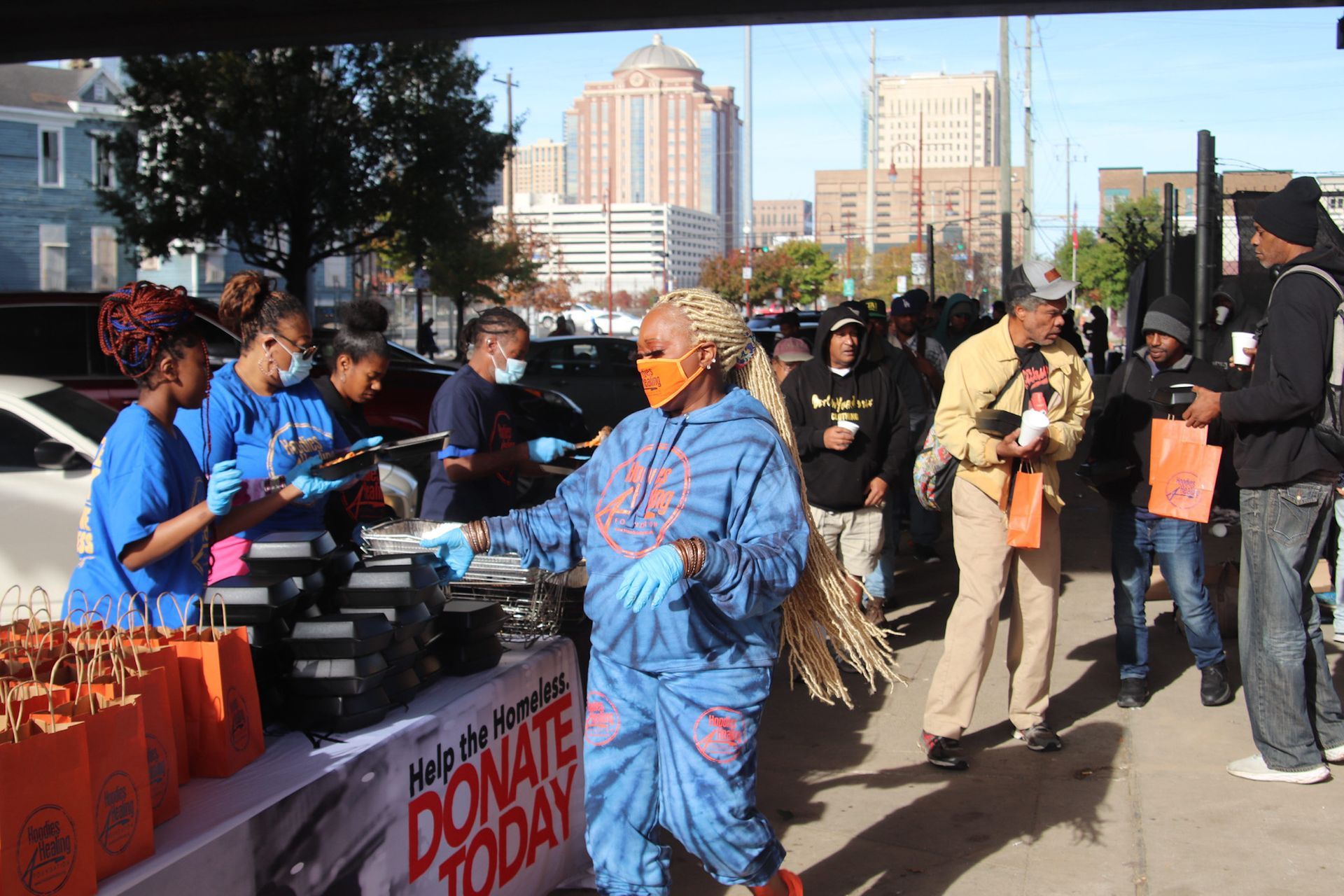 A group of people are standing around a table that says donate today.