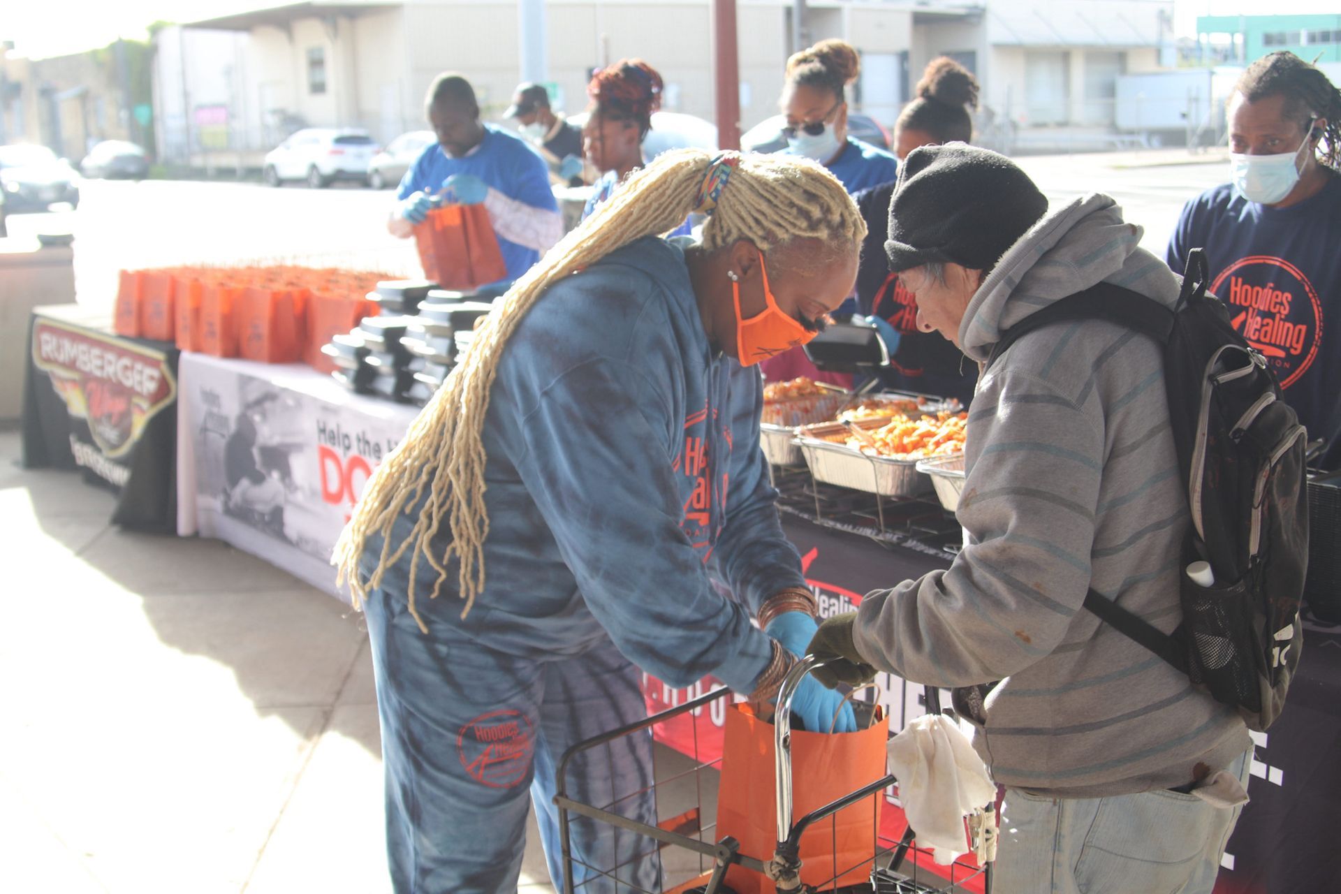 A group of people are standing around a table with food.