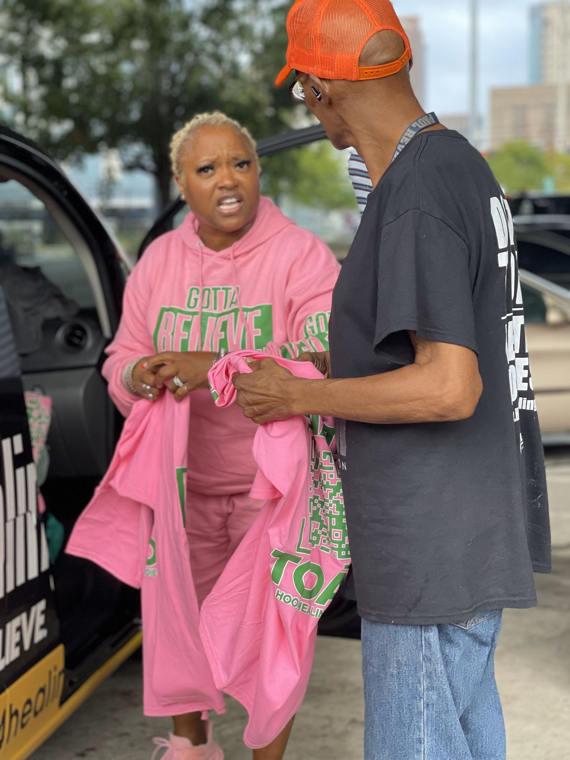 A man and a woman are standing next to each other in front of a car.