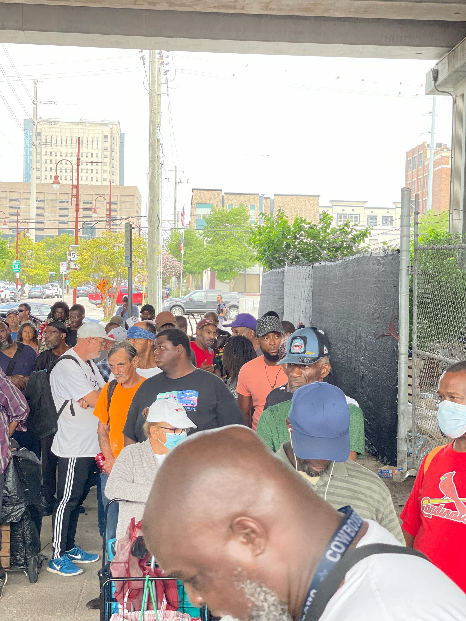 A man wearing a camera strap is standing in front of a crowd of people.