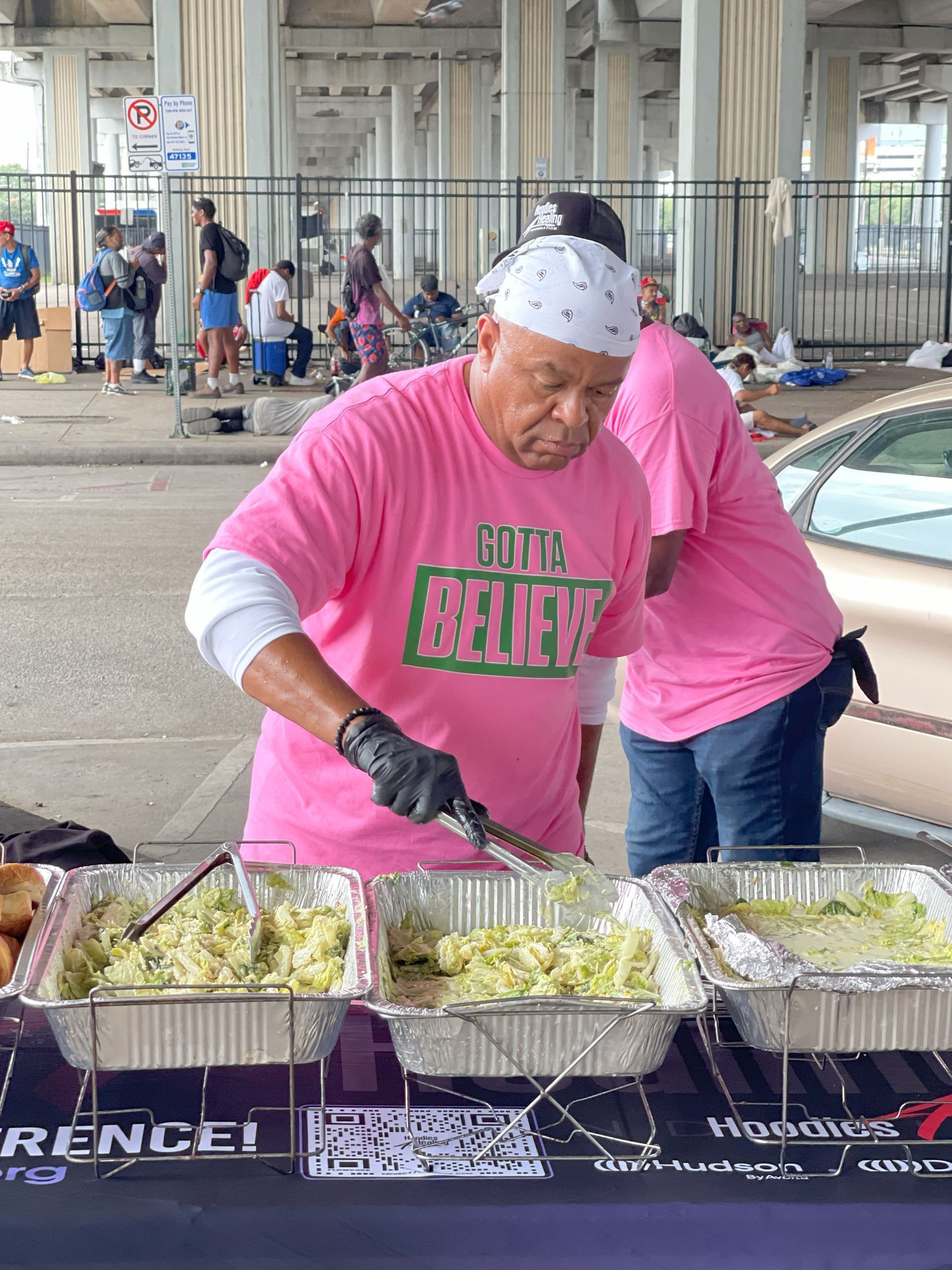 A man in a pink shirt is preparing food at a table.