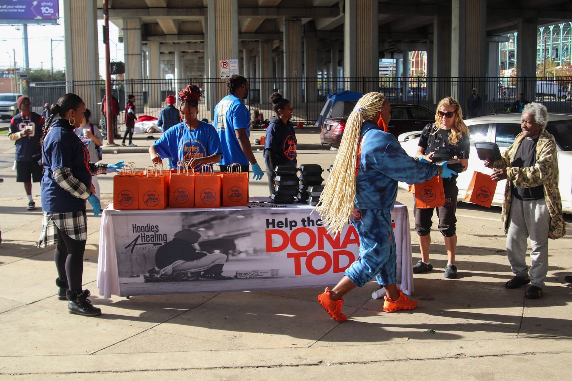 A group of people are standing around a table that says help the dona top