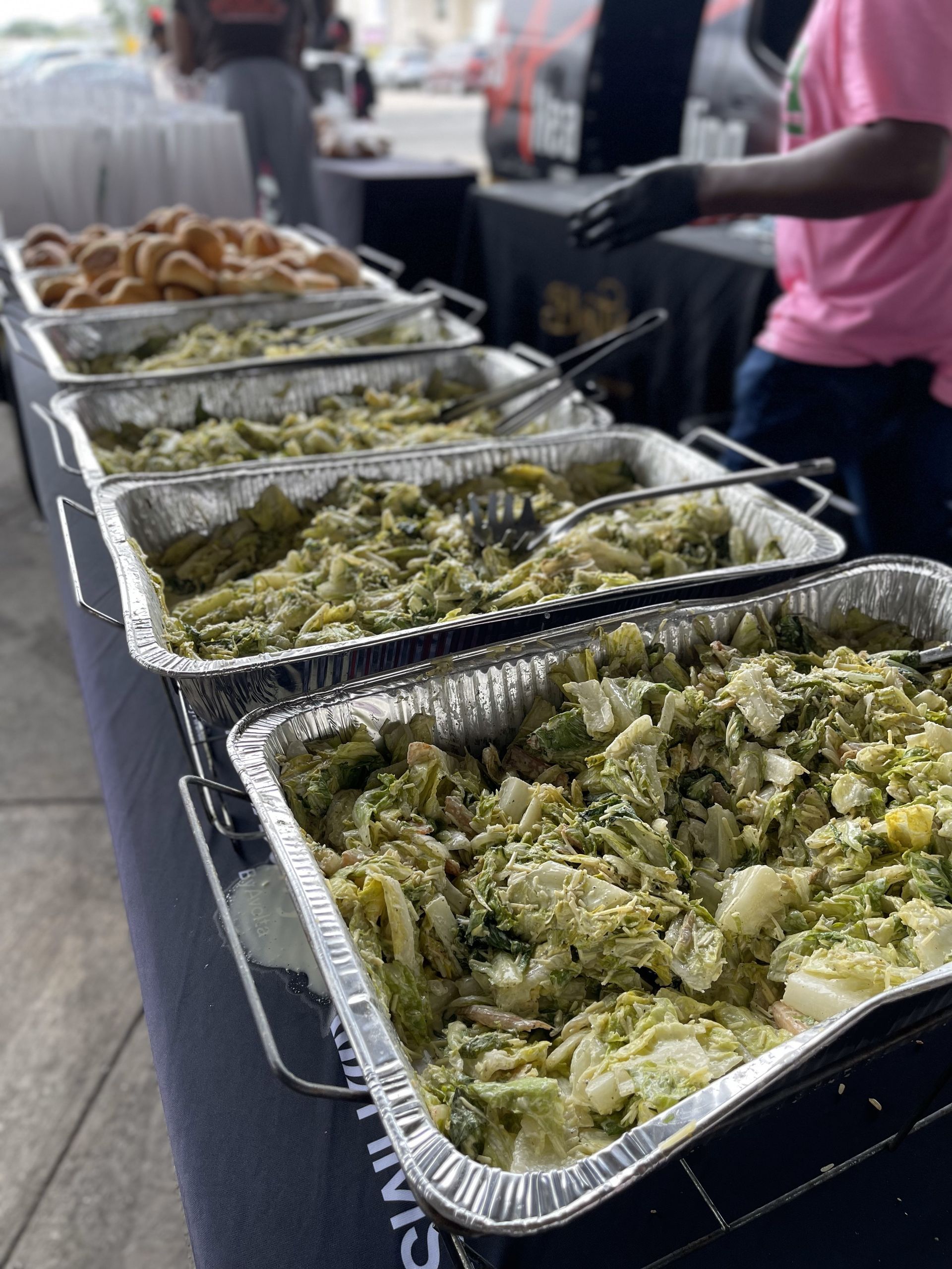 A row of aluminum foil trays filled with food on a table.