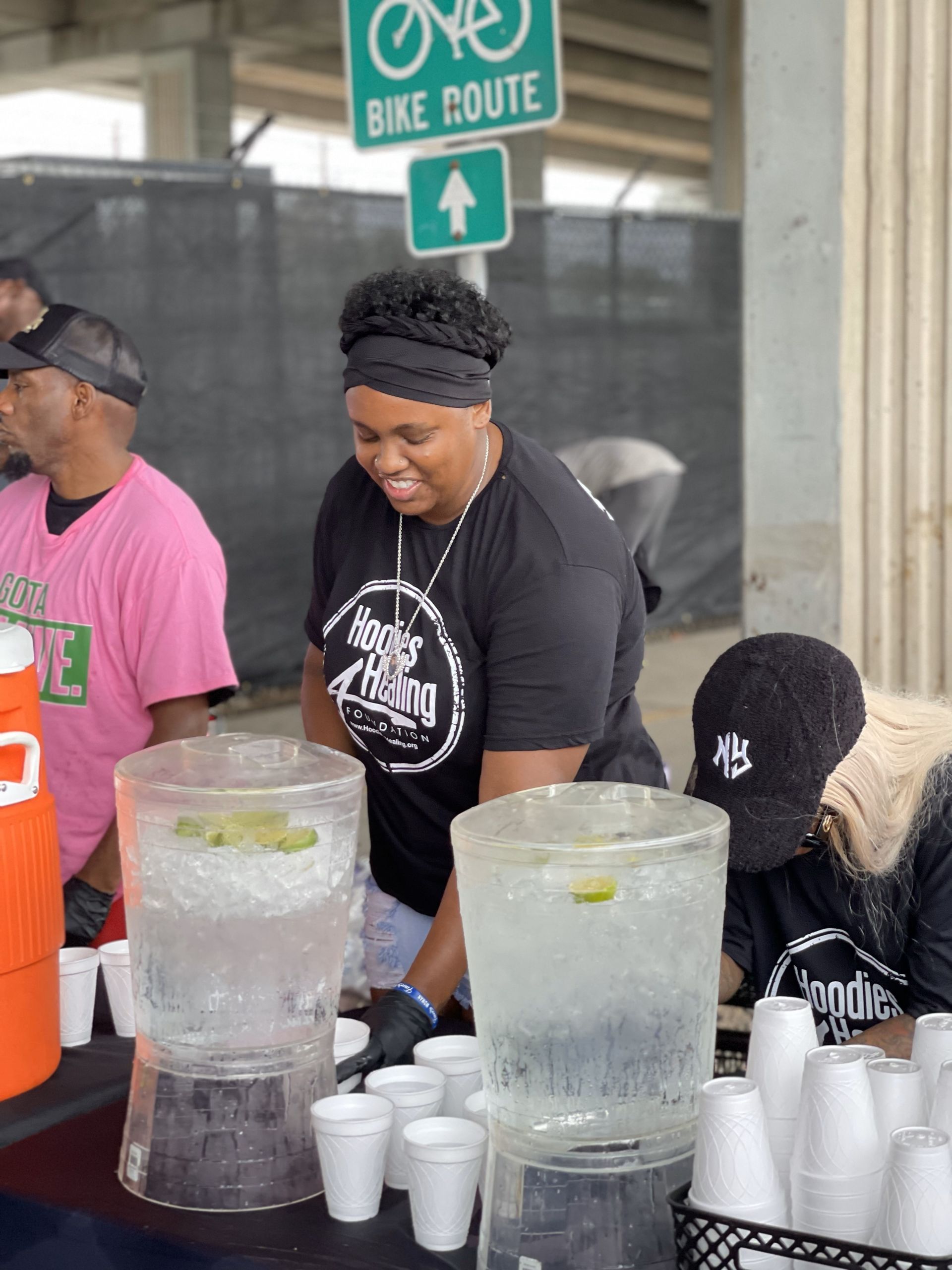 A woman is standing behind a table filled with ice and cups.