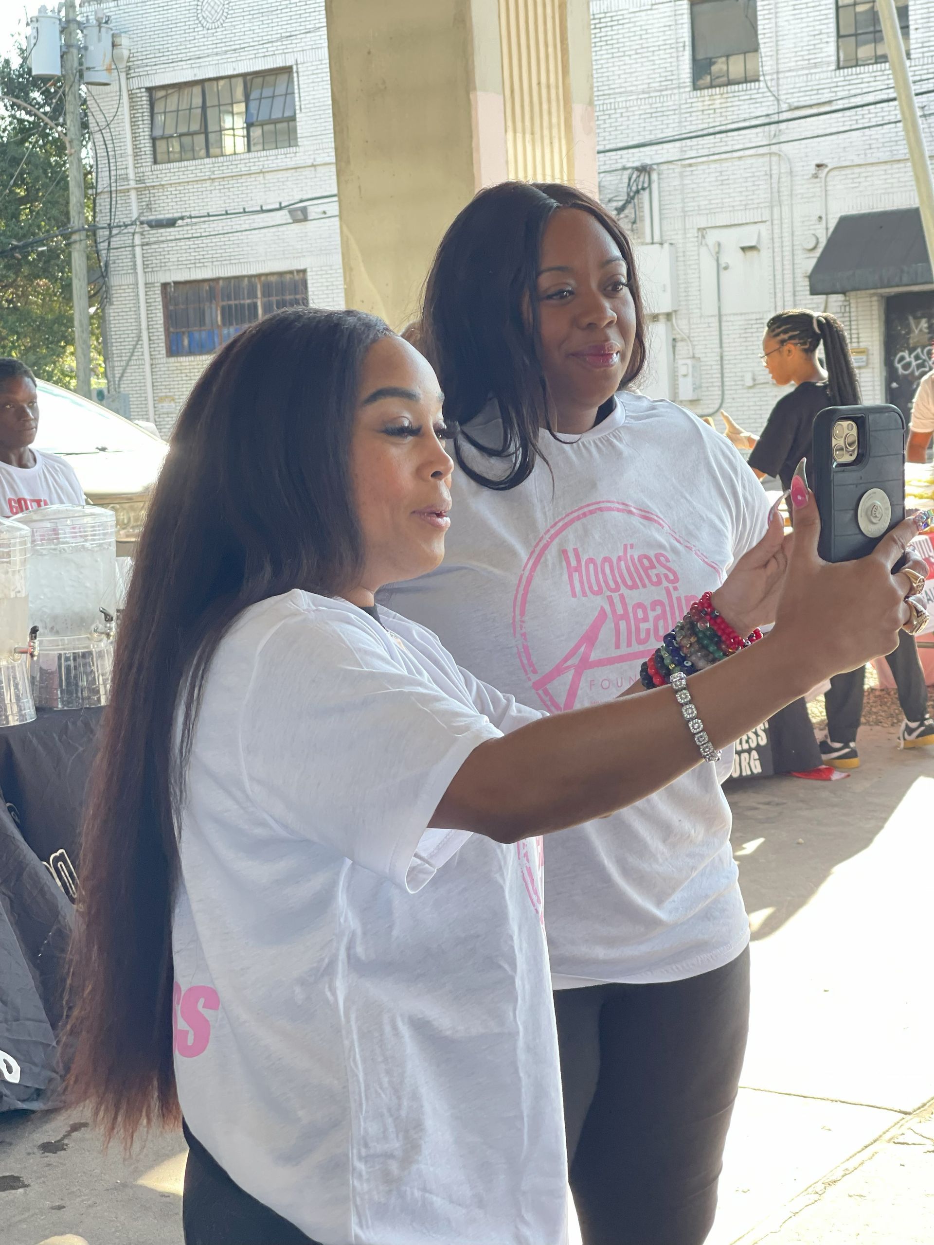 Two women are taking a selfie with a cell phone.