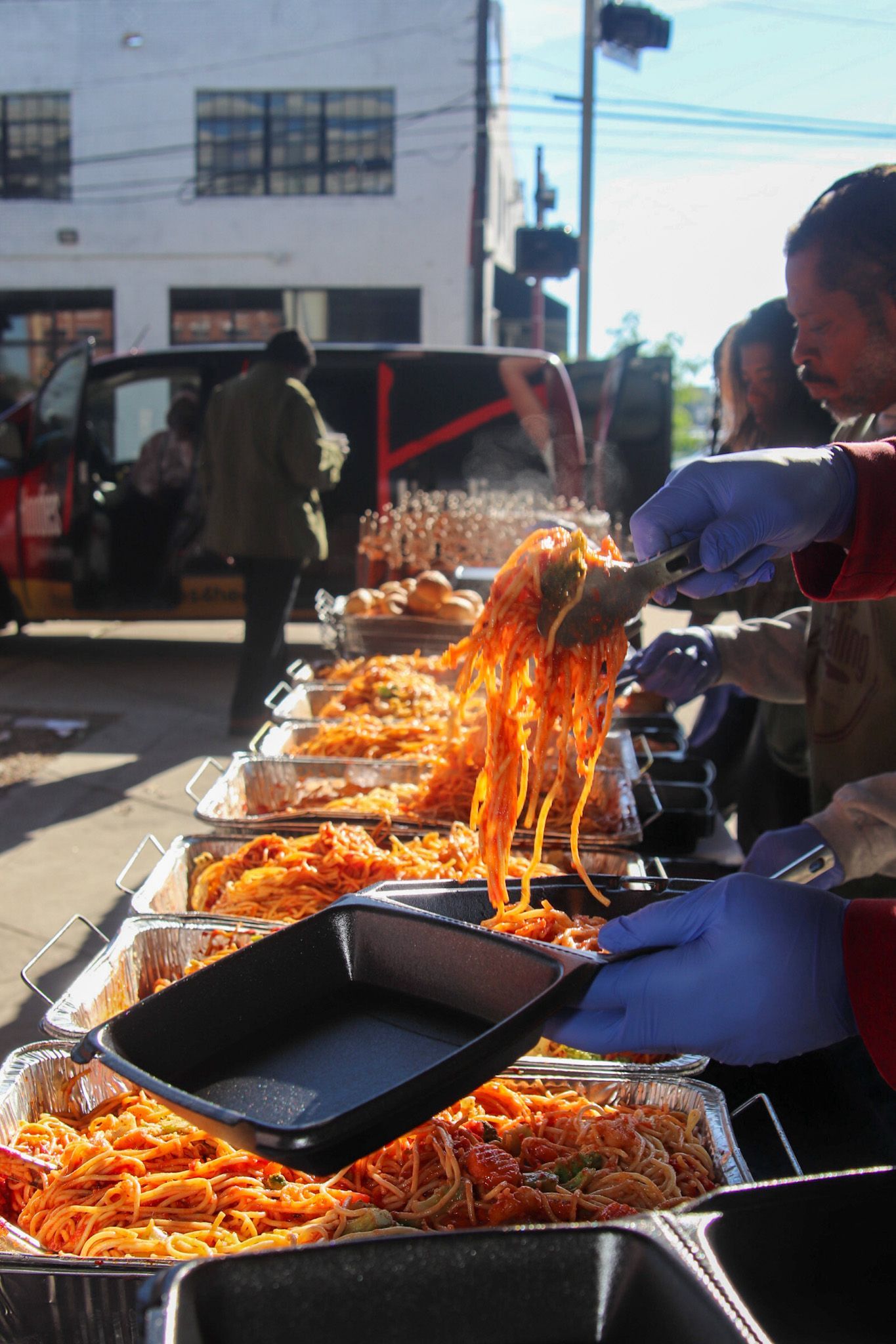 A man wearing blue gloves is serving food at a buffet table.