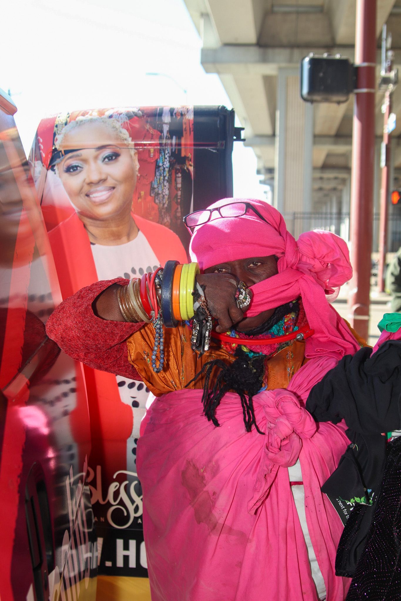 A woman in a pink dress is standing in front of a bus.