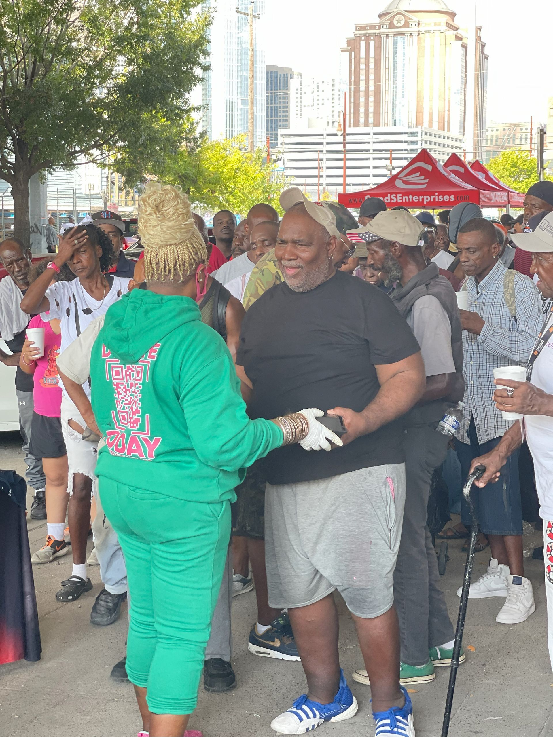 A woman in a green hoodie is shaking hands with a man in a black shirt.