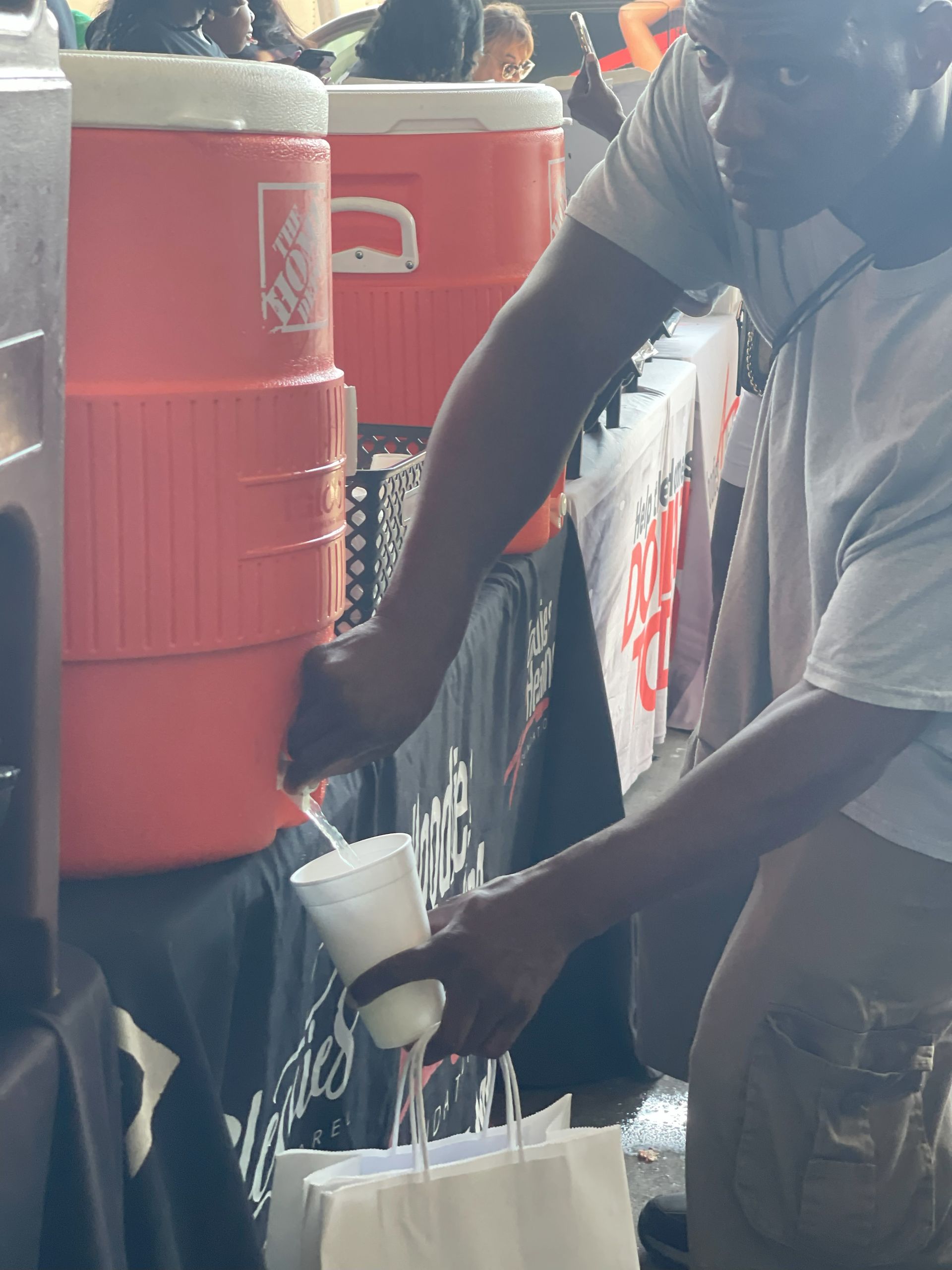 A man is pouring water from a cooler into a cup