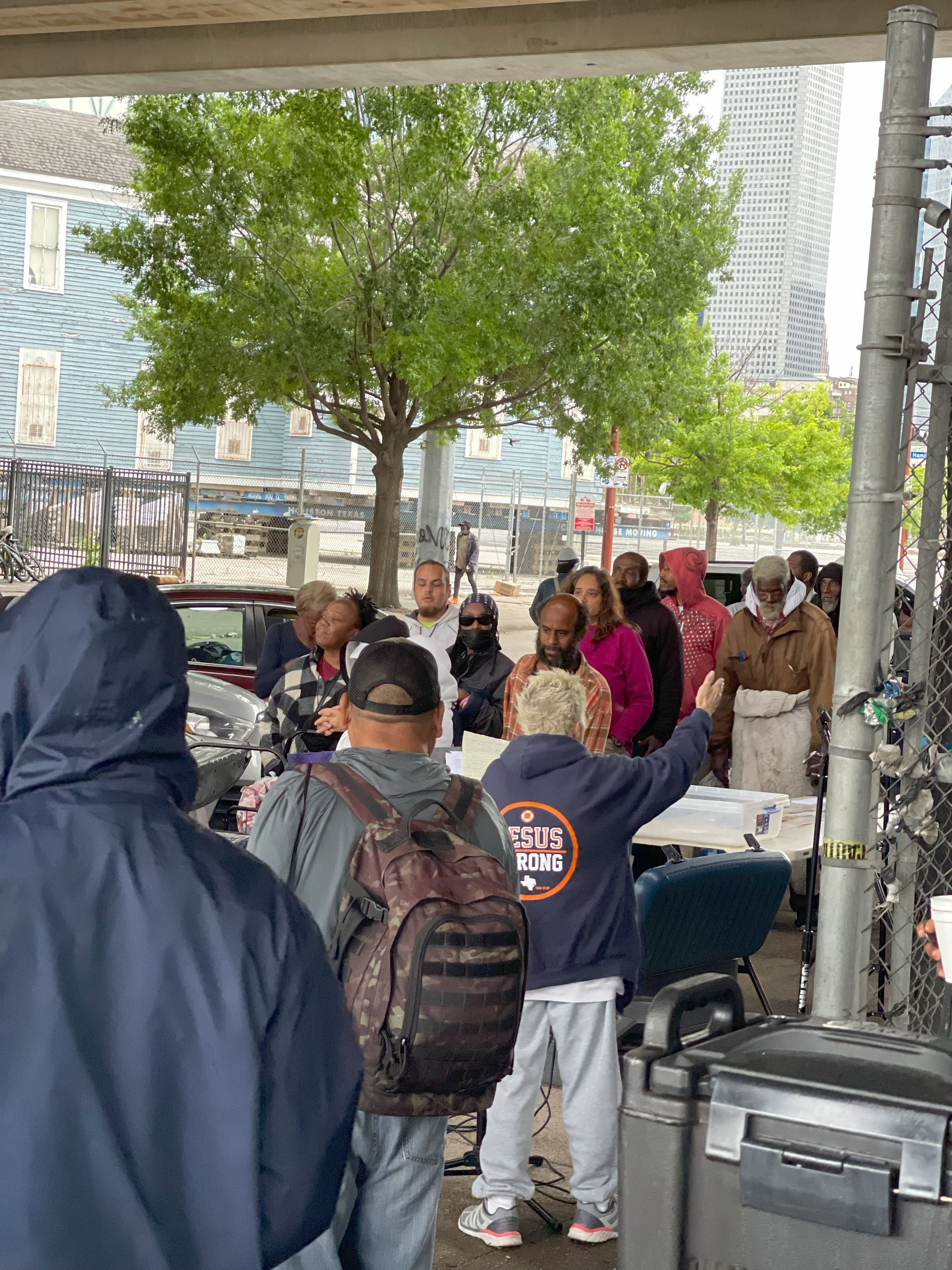 A group of people are standing in a line under a bridge.