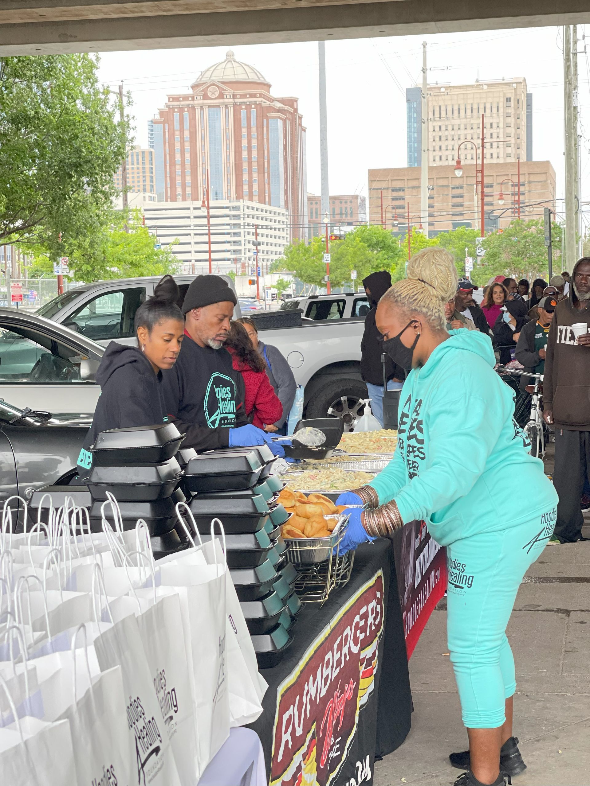 A woman in a blue hoodie is standing in front of a table with a sign that says ' a cup ' on it