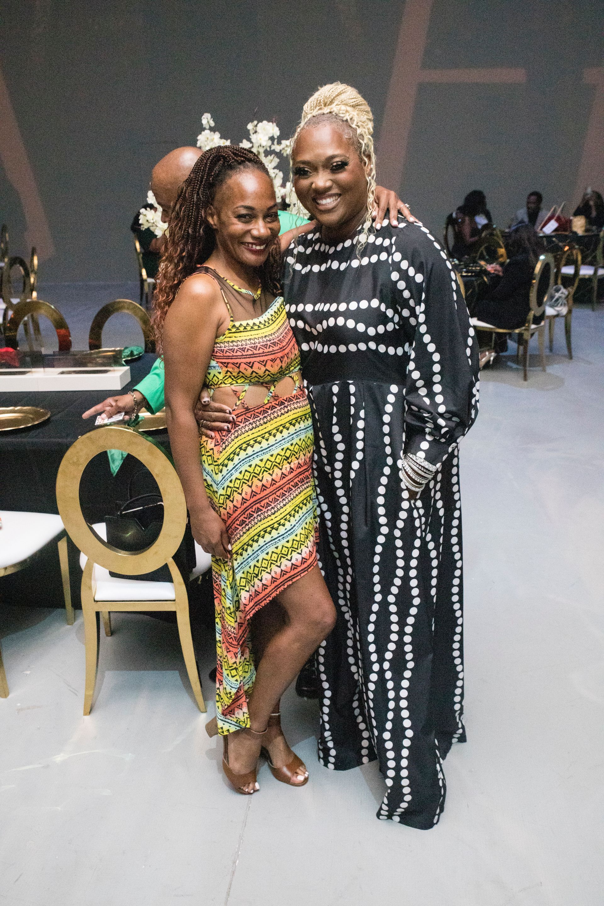 Two women are posing for a picture in a room with chairs.