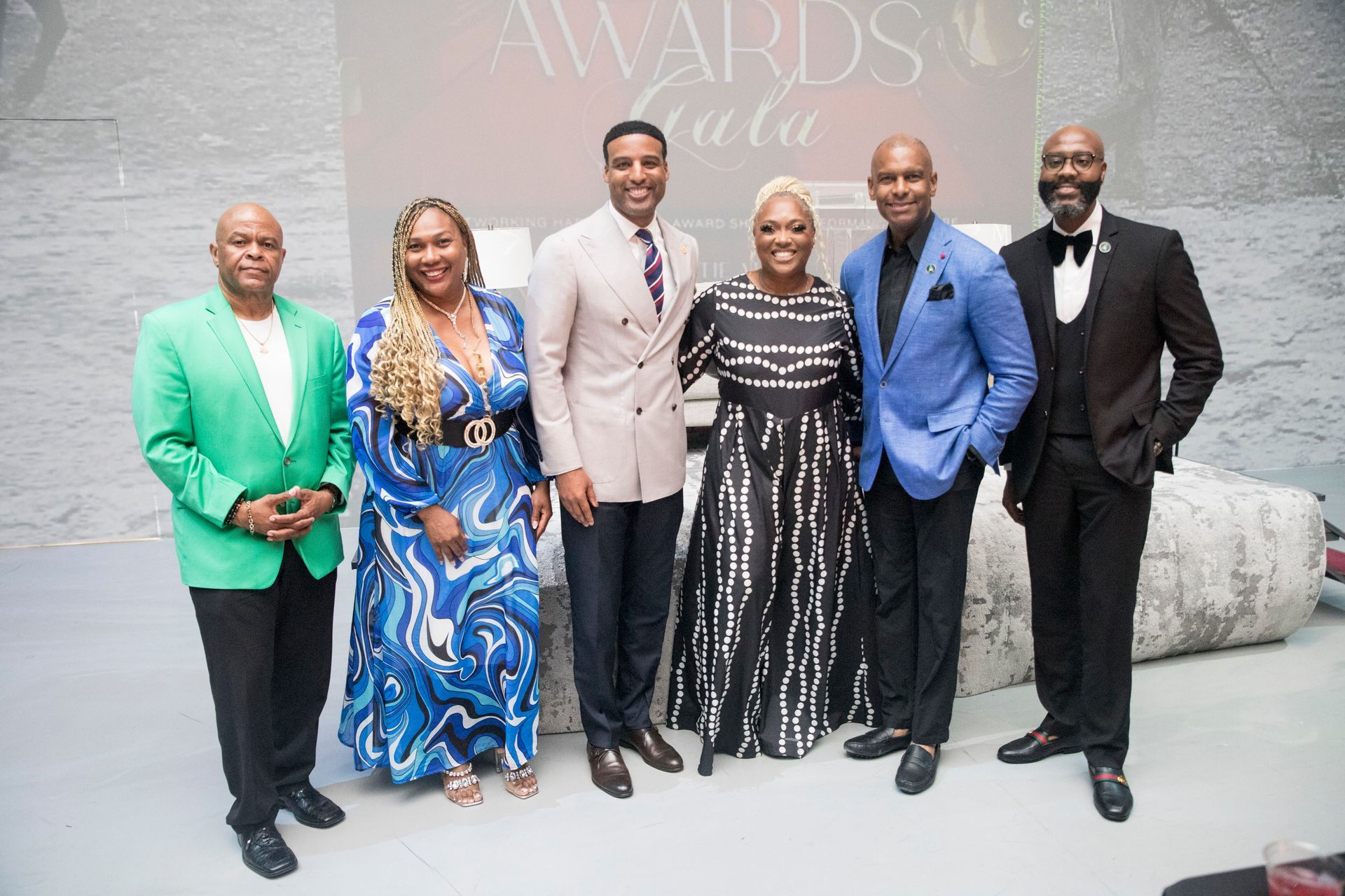 A group of people are posing for a picture in front of a wall that says awards gala.
