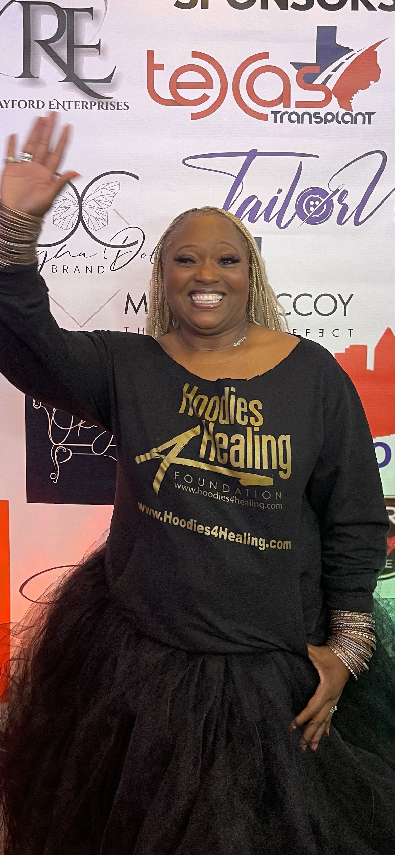 A woman wearing a black shirt and a black skirt is standing in front of a sign.