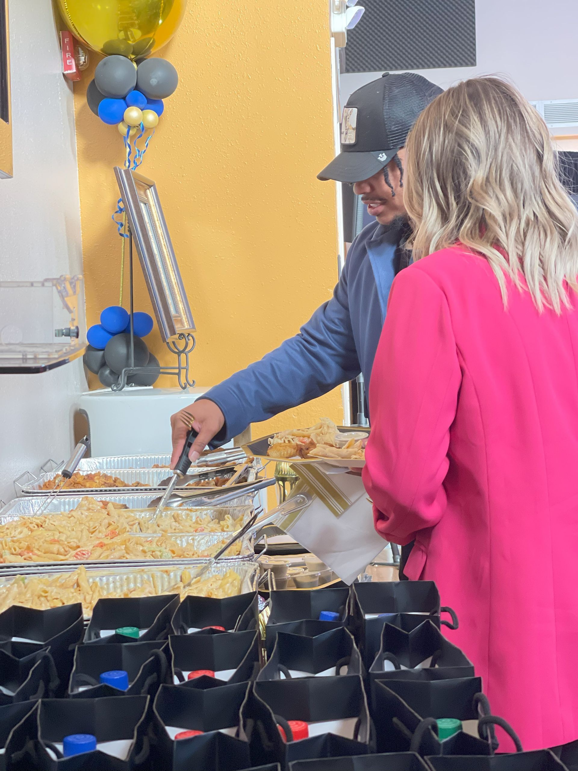 A man and a woman are standing at a buffet table.