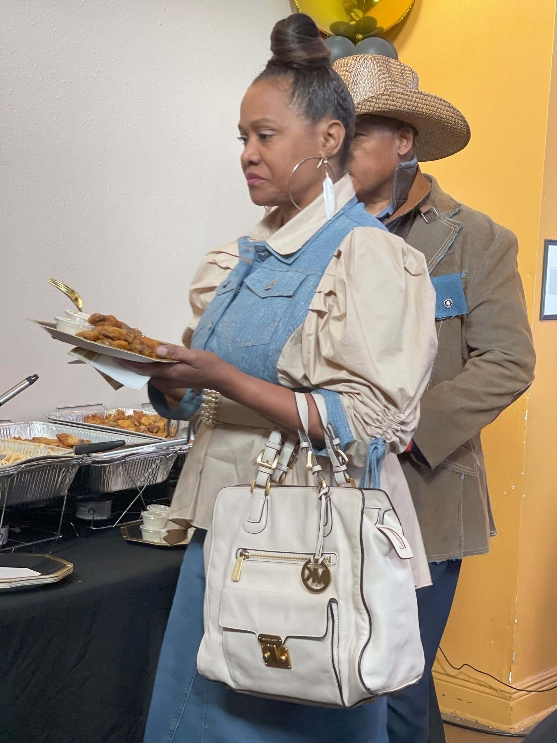 A woman in a cowboy hat is holding a plate of food