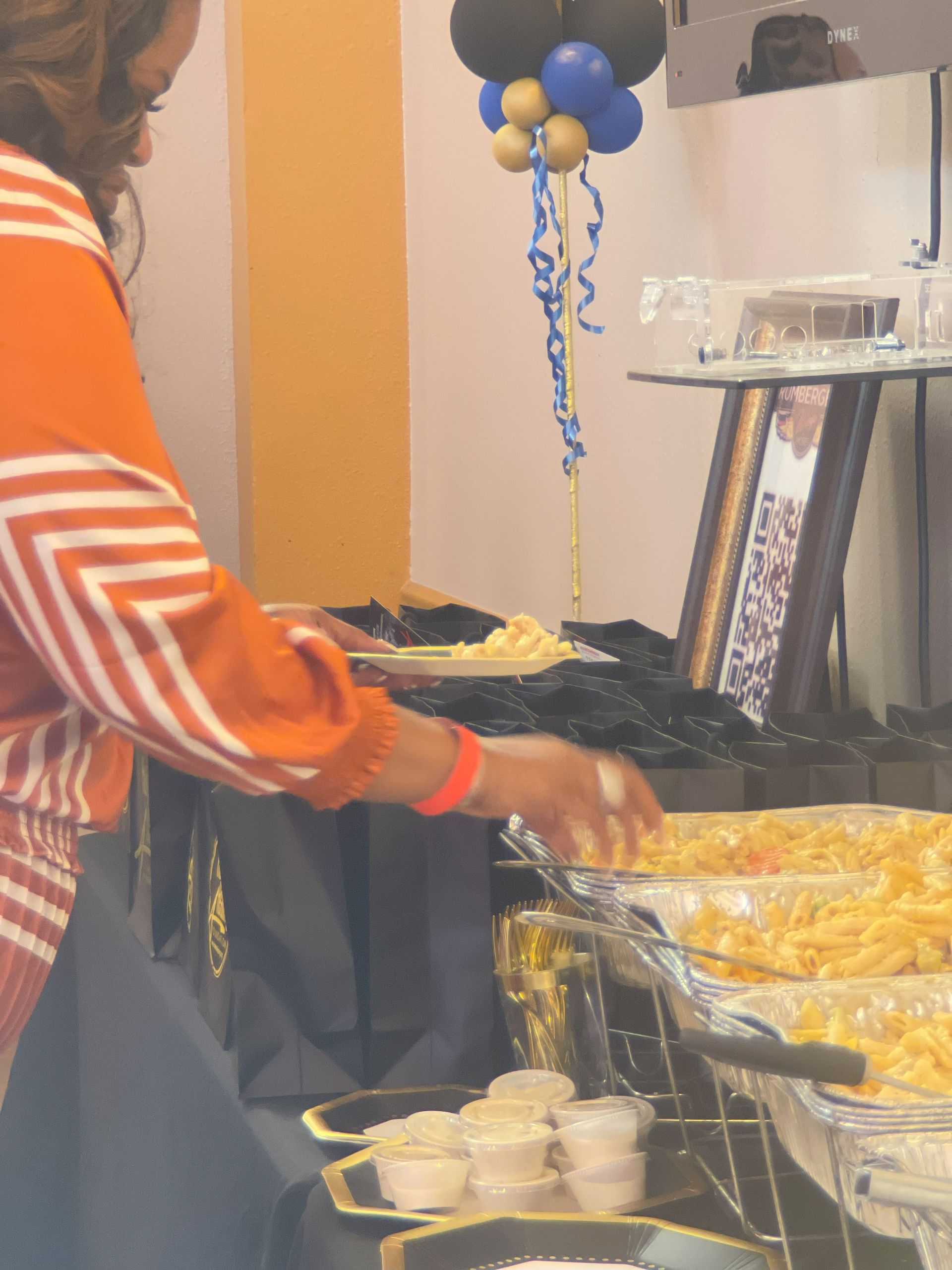 A woman is serving food at a buffet table with balloons in the background