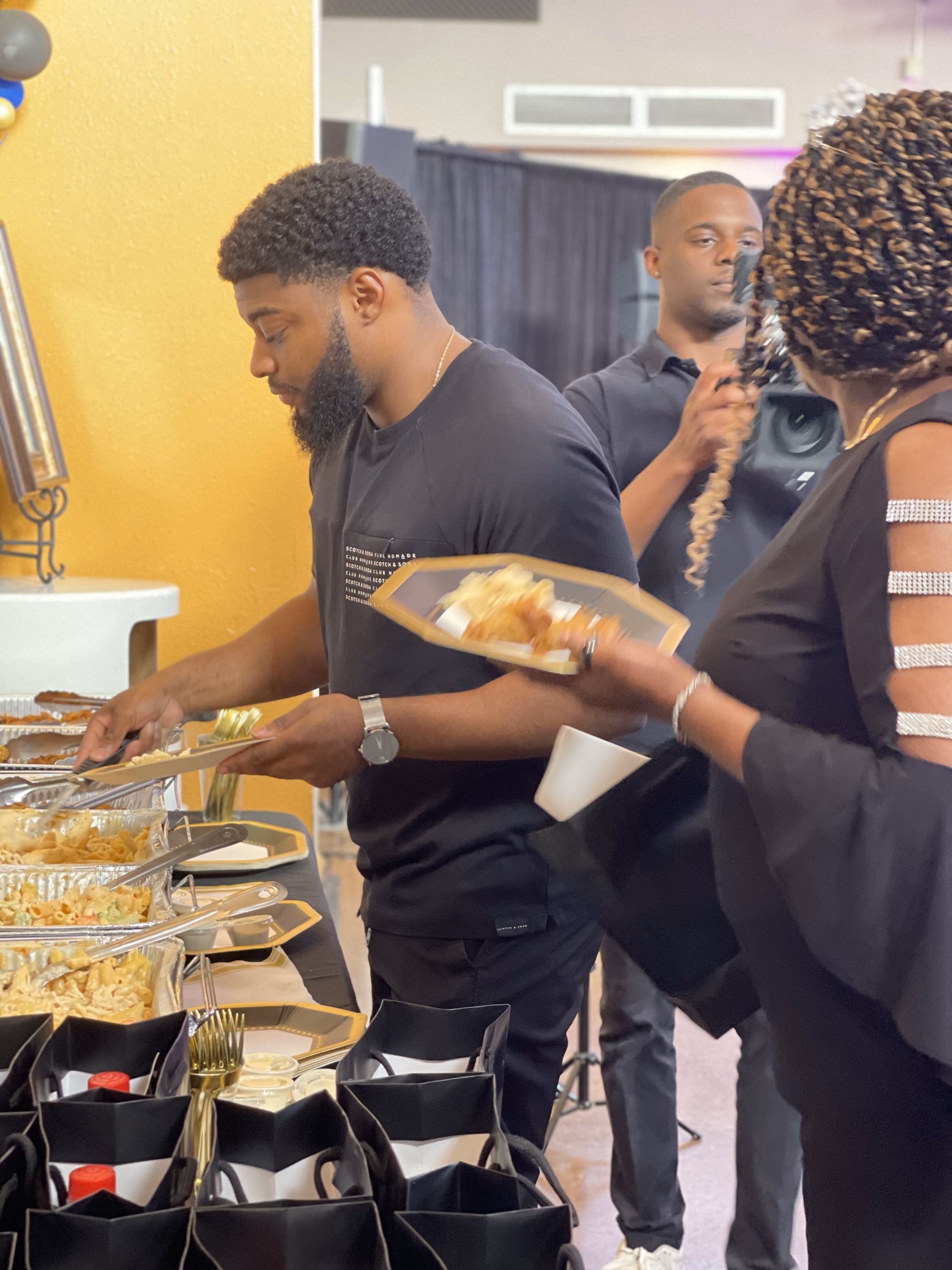 A group of people are standing around a table eating food.