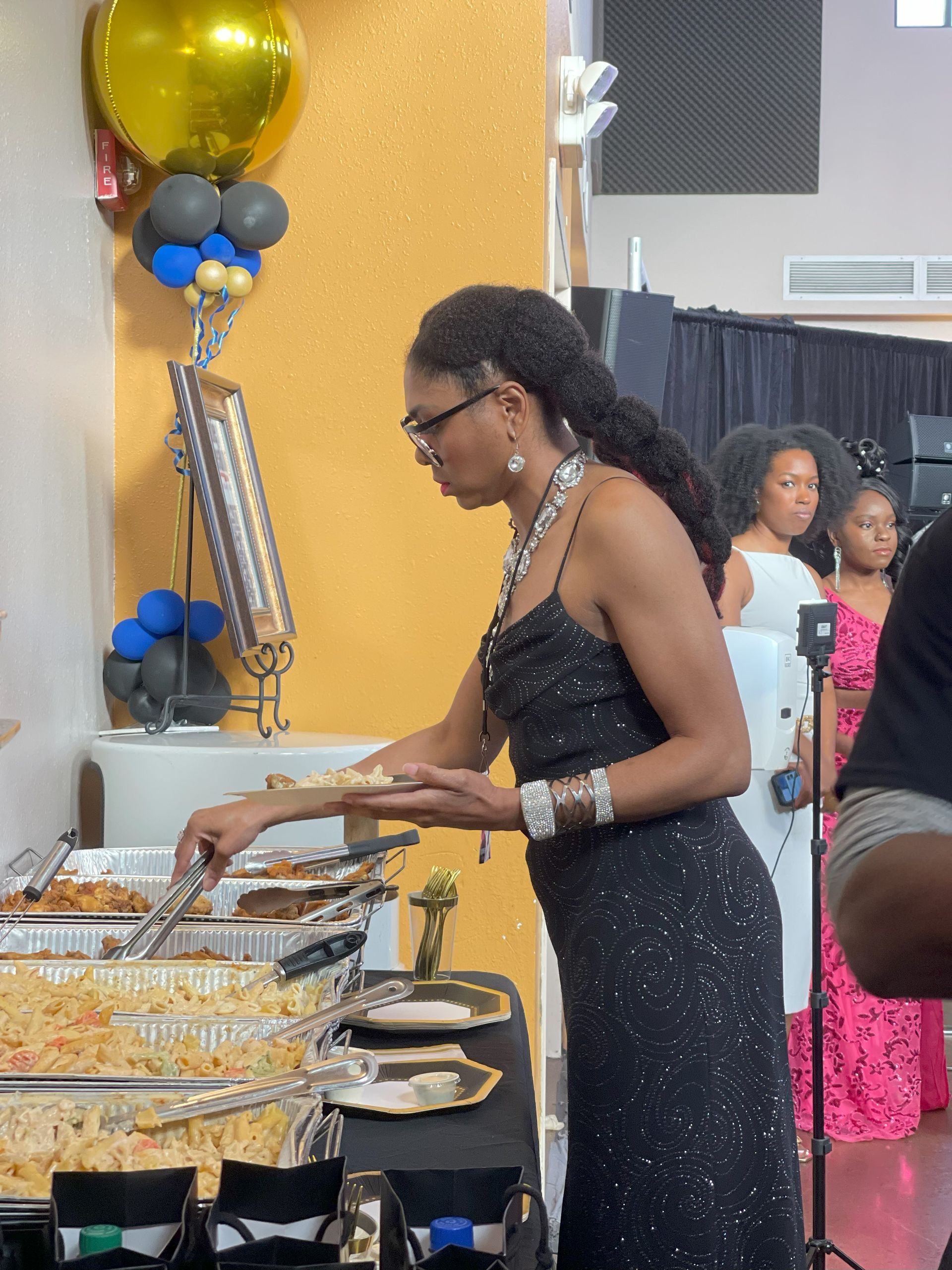 A woman in a black dress is serving food at a party