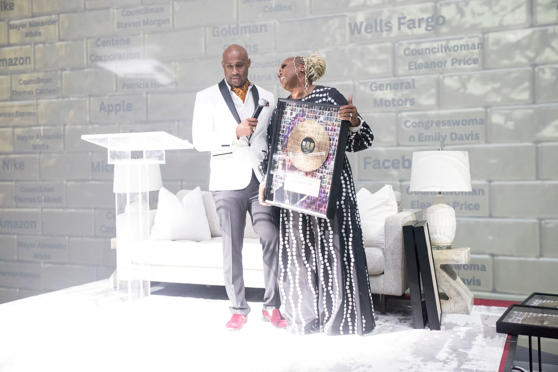 A man and a woman are standing next to each other in front of a brick wall.