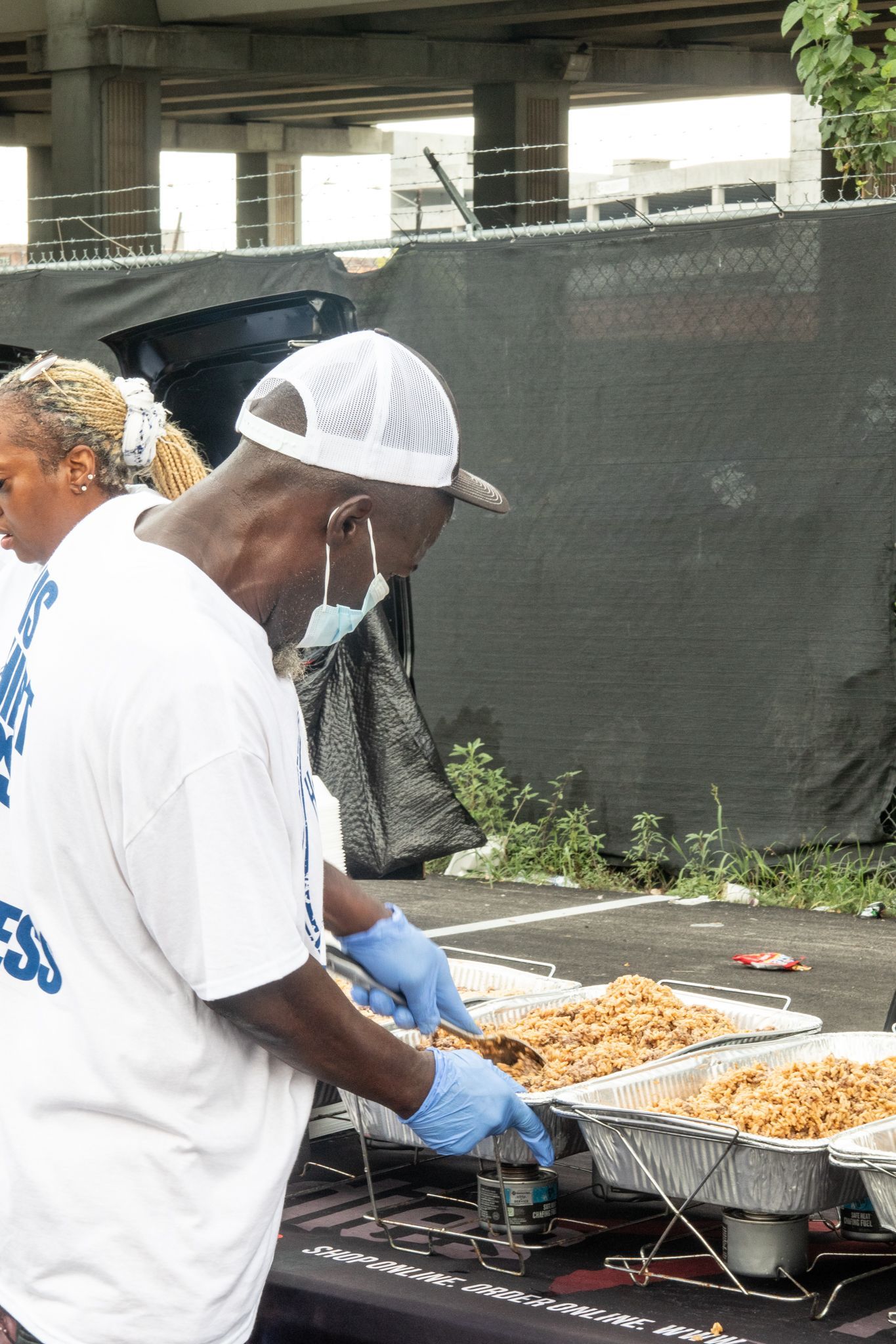A man in a white shirt is standing in front of a table filled with food.
