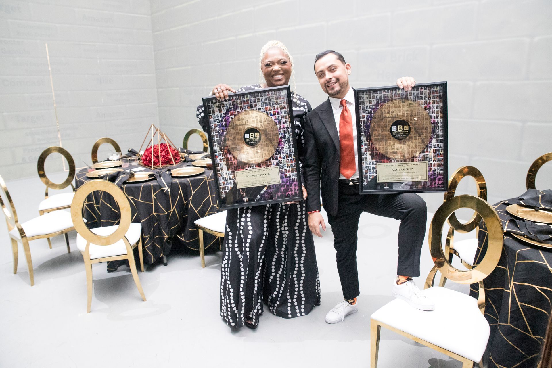A man and a woman are holding plaques in a room with tables and chairs.