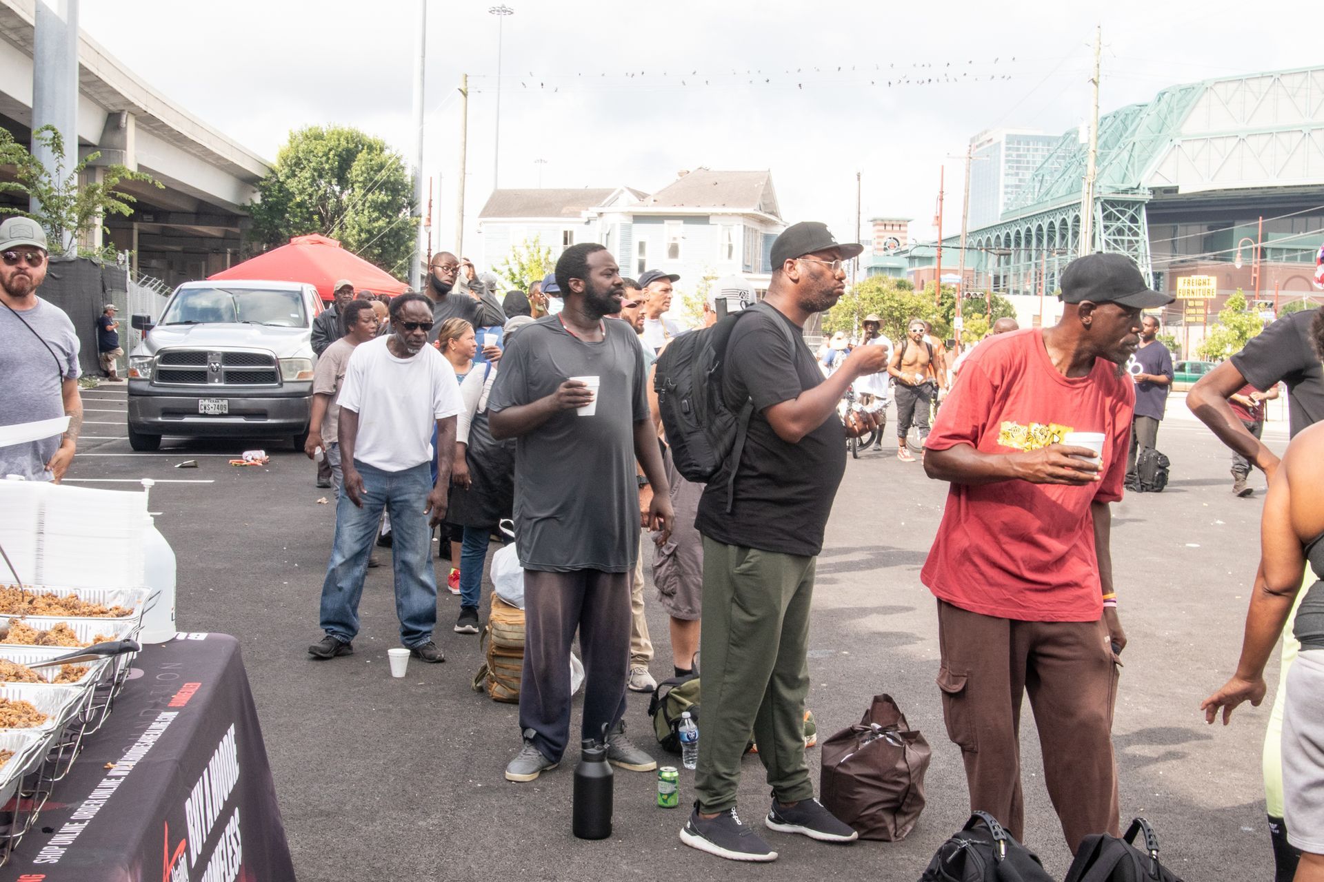 A group of men are standing in a parking lot talking to each other.