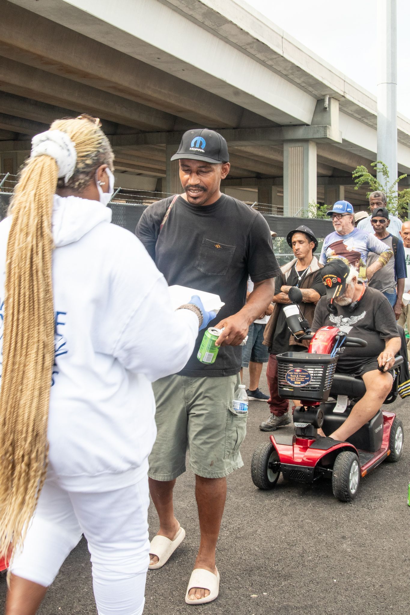 A woman wearing a mask is talking to a man in a scooter.