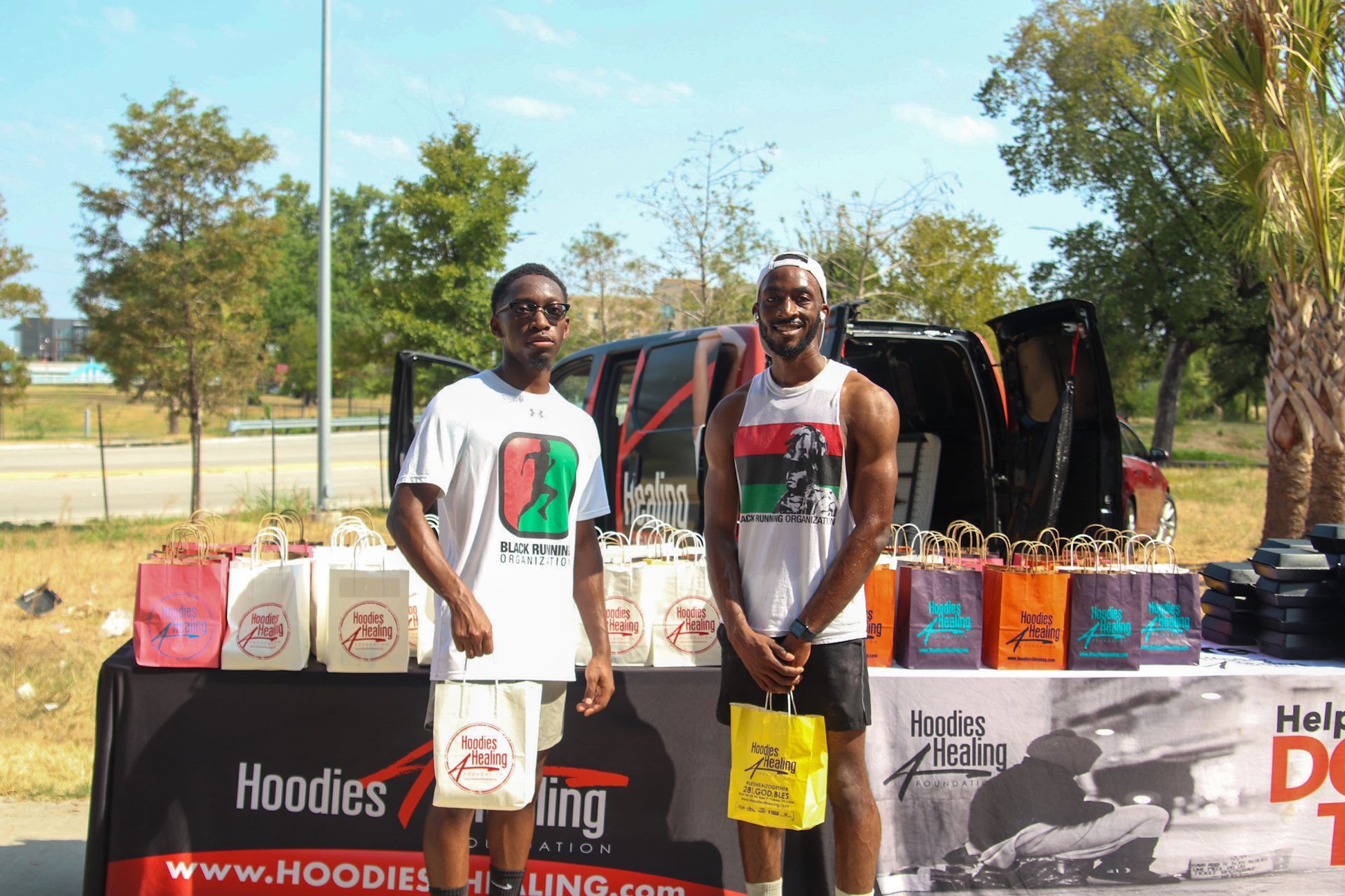 Two men standing in front of a table that says hoodies