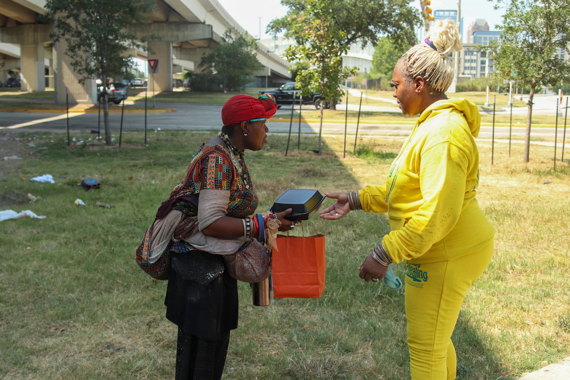 A woman in a yellow outfit is talking to another woman in a red hat.