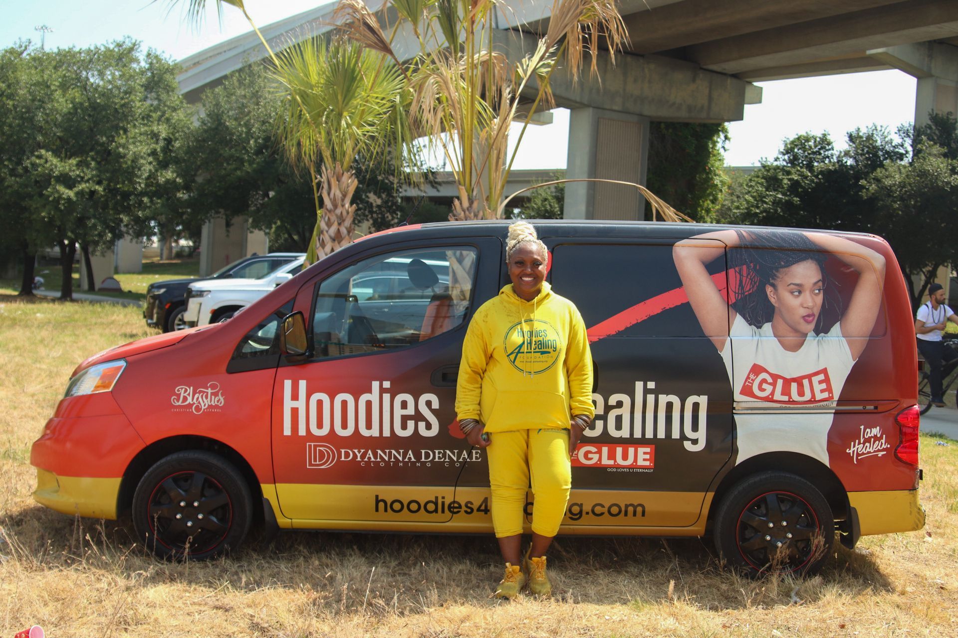 A woman is standing in front of a van that says hoodies