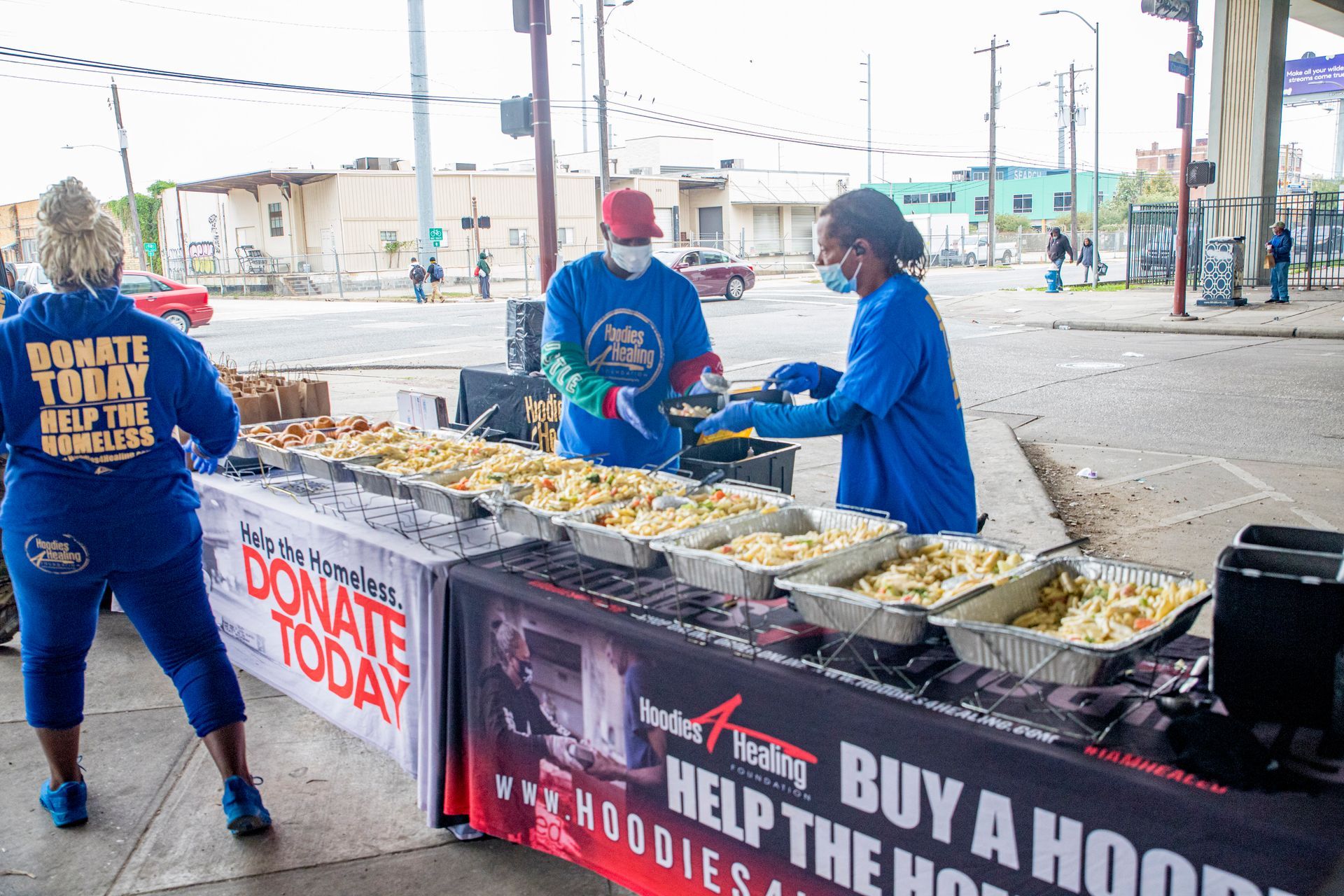 A group of people are standing around a table filled with food.