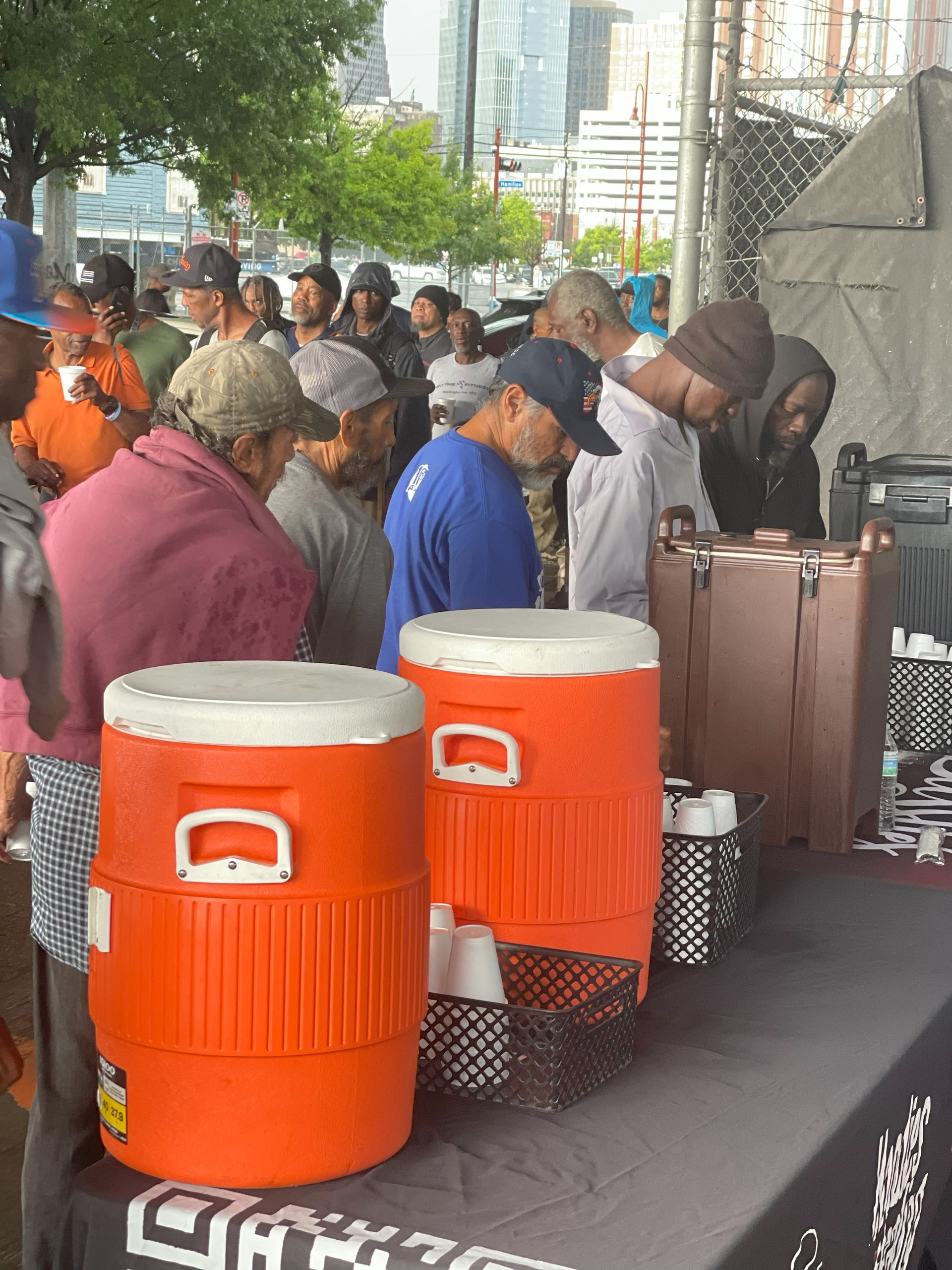 A group of people are standing around a table with coolers on it